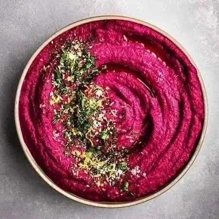 Vibrant organic purple beet hummus garnished with chopped pistachio and lemon zest. Organic food. Healthy food.
