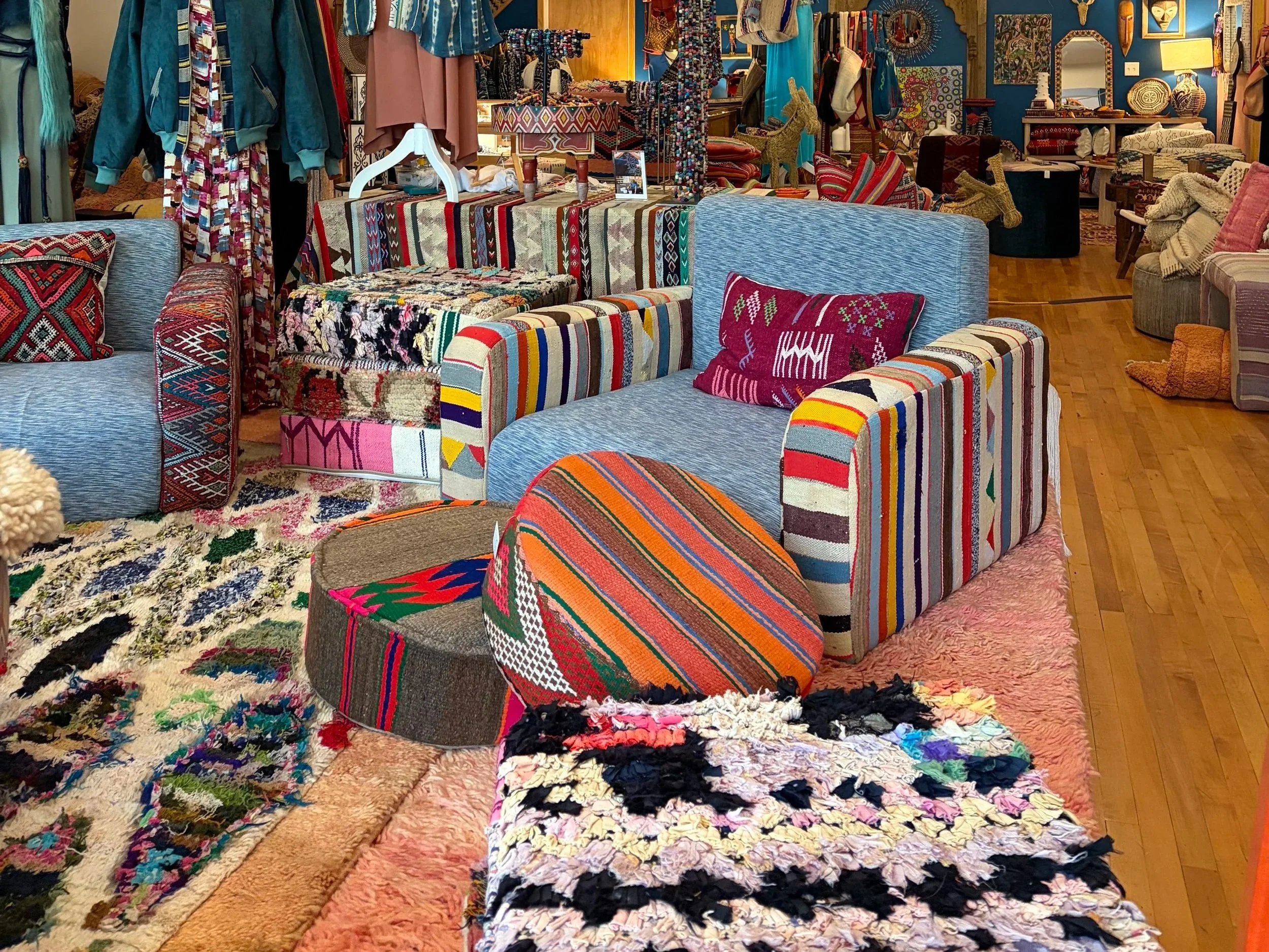A room filled with various colorful handwoven and patterned textiles, cushions, and furniture, creating a vibrant and eclectic atmosphere.