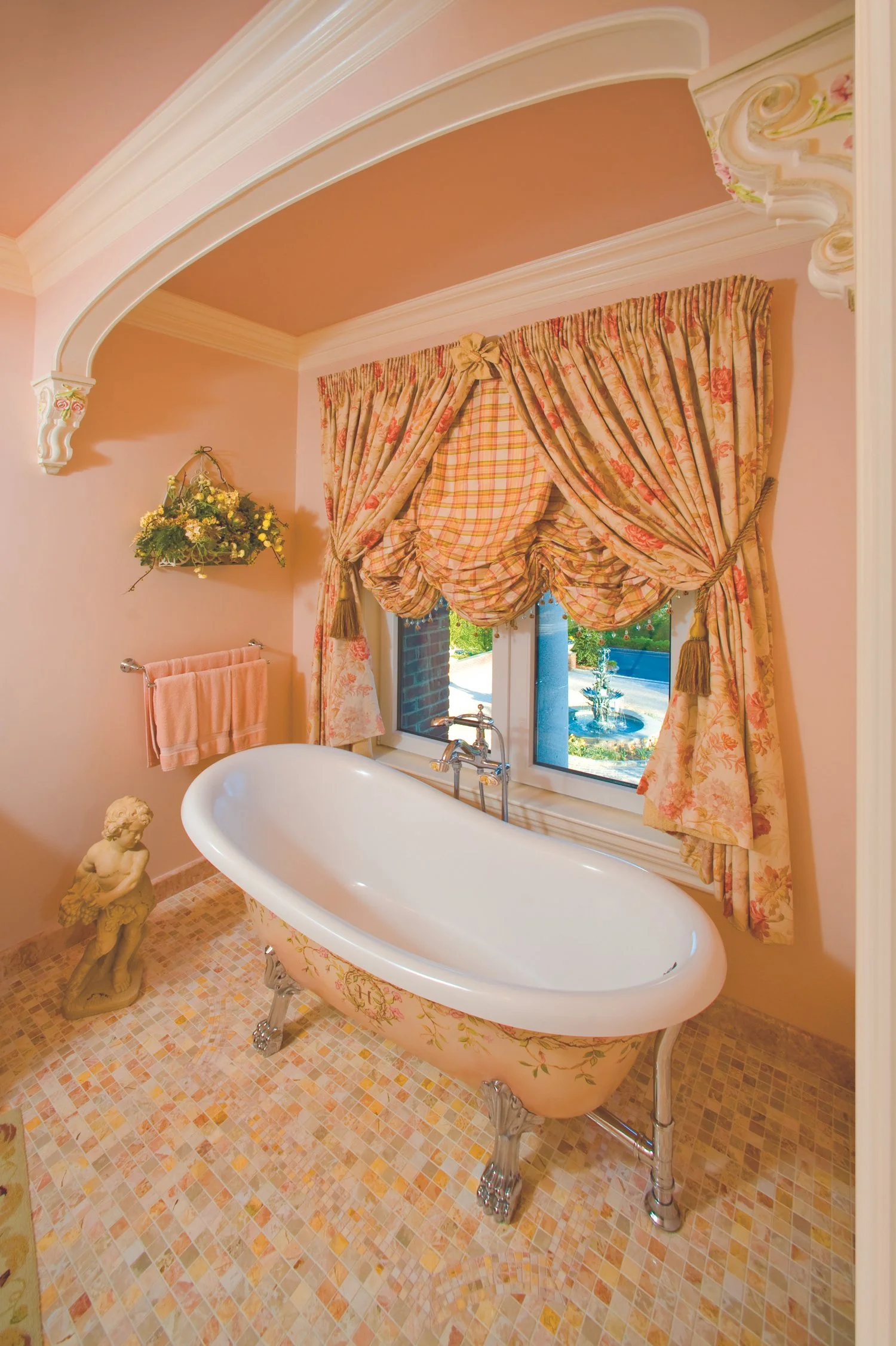 A vintage-style bathroom with a white clawfoot bathtub, floral curtains, and a decorative cherub statue.