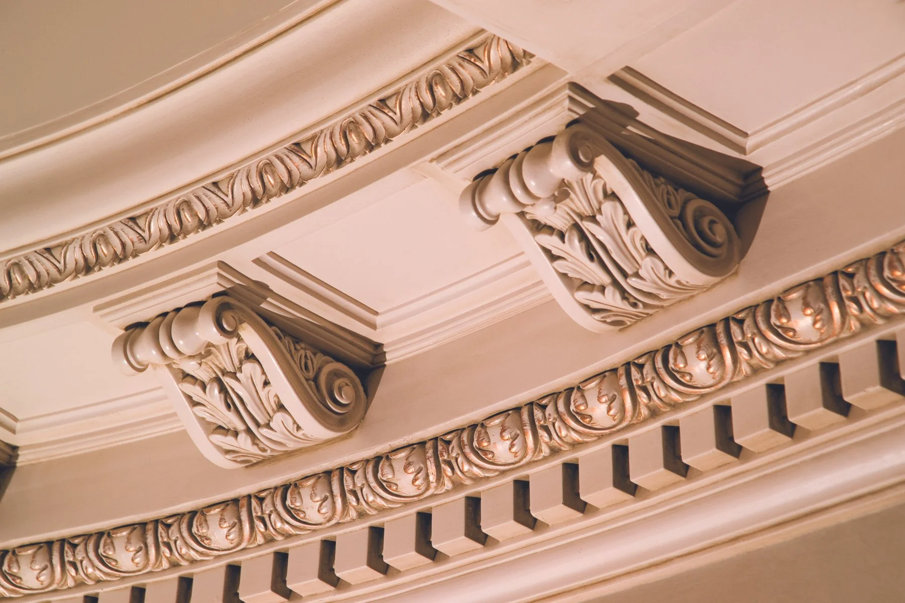 Close-up of ornate crown molding with intricate scrollwork and decorative trims on a ceiling.