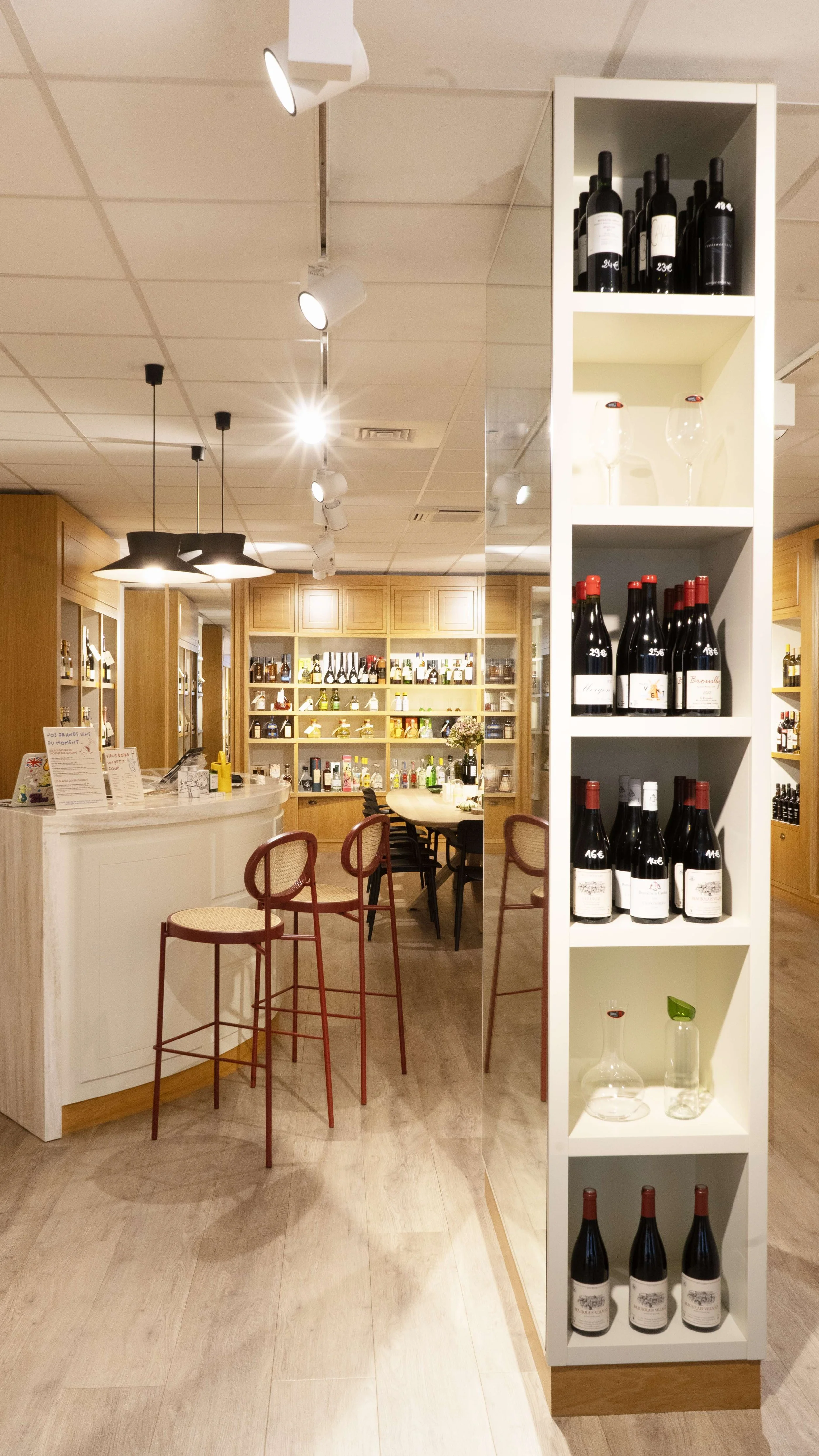 Intérieur d'un bar avec des étagères remplies de bouteilles de vin, une table ronde avec des chaises et un comptoir en bois clair endroit pour boire un verre dans la ville de Vernon à côté de Giverny dans l'Eure en Normandie