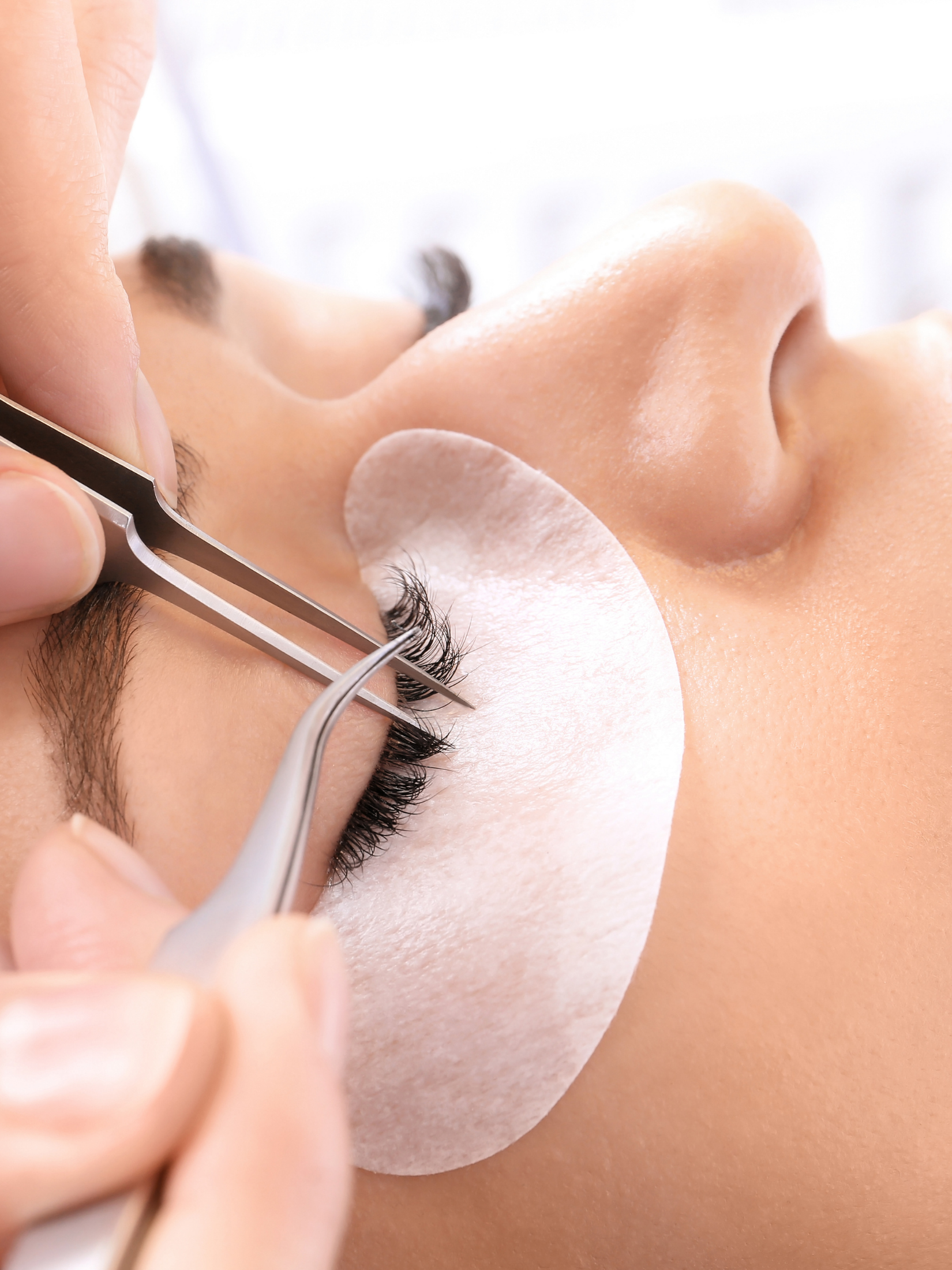 Person receiving a professional facial treatment, lying down with a white facial mask and skincare tools applied by a skincare specialist.