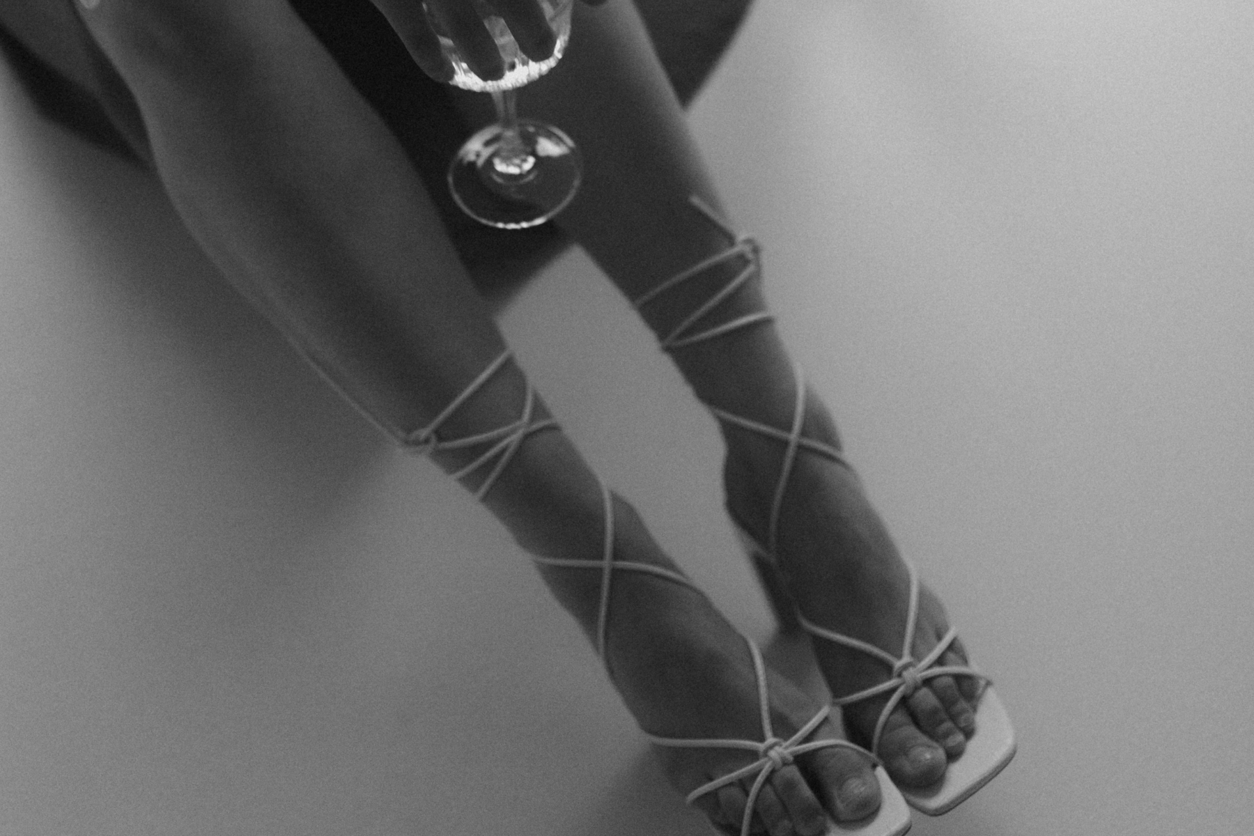 Black and white close-up photo of two intertwined Christmas candy cane decorations with white crisscrossed ribbon tied in bows, on a plain background.