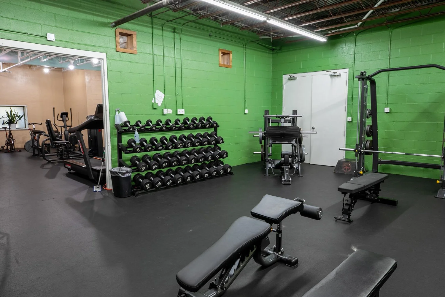Free weights and cardio equipment in the gym area of Iron Club in East Point Georgia, in the downstairs of Phys. Ed.