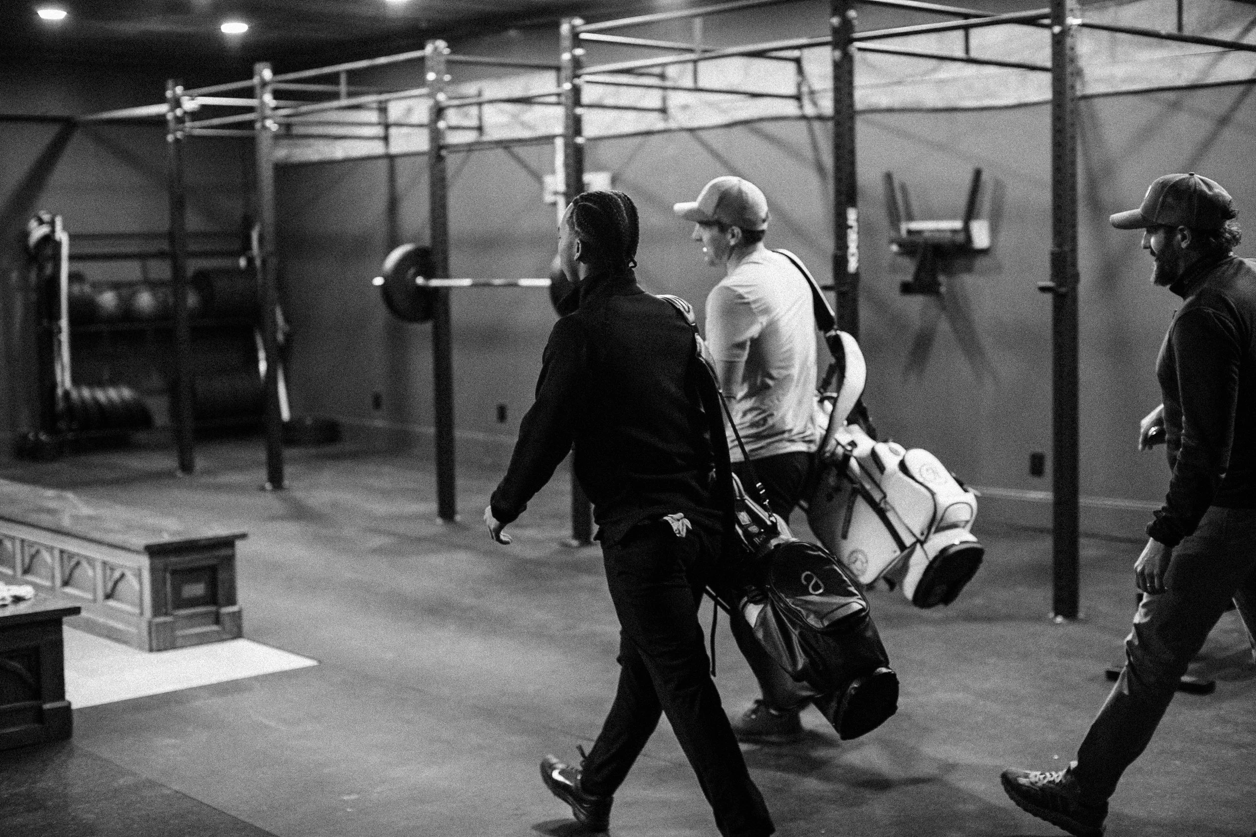 Group of golfers walking into their fitness training center with their golf clubs