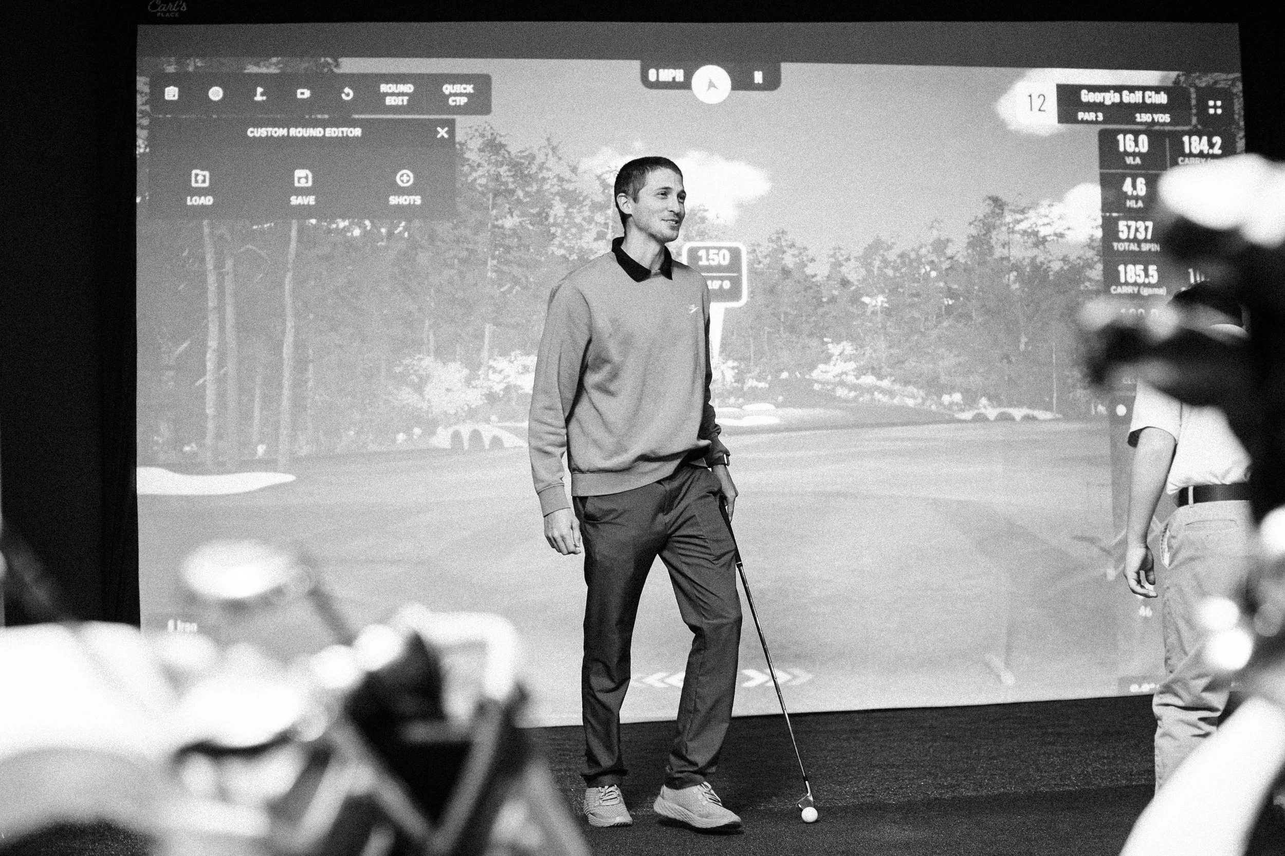 A man finishing his golf swing at a Fairburn Golf Simulator Club