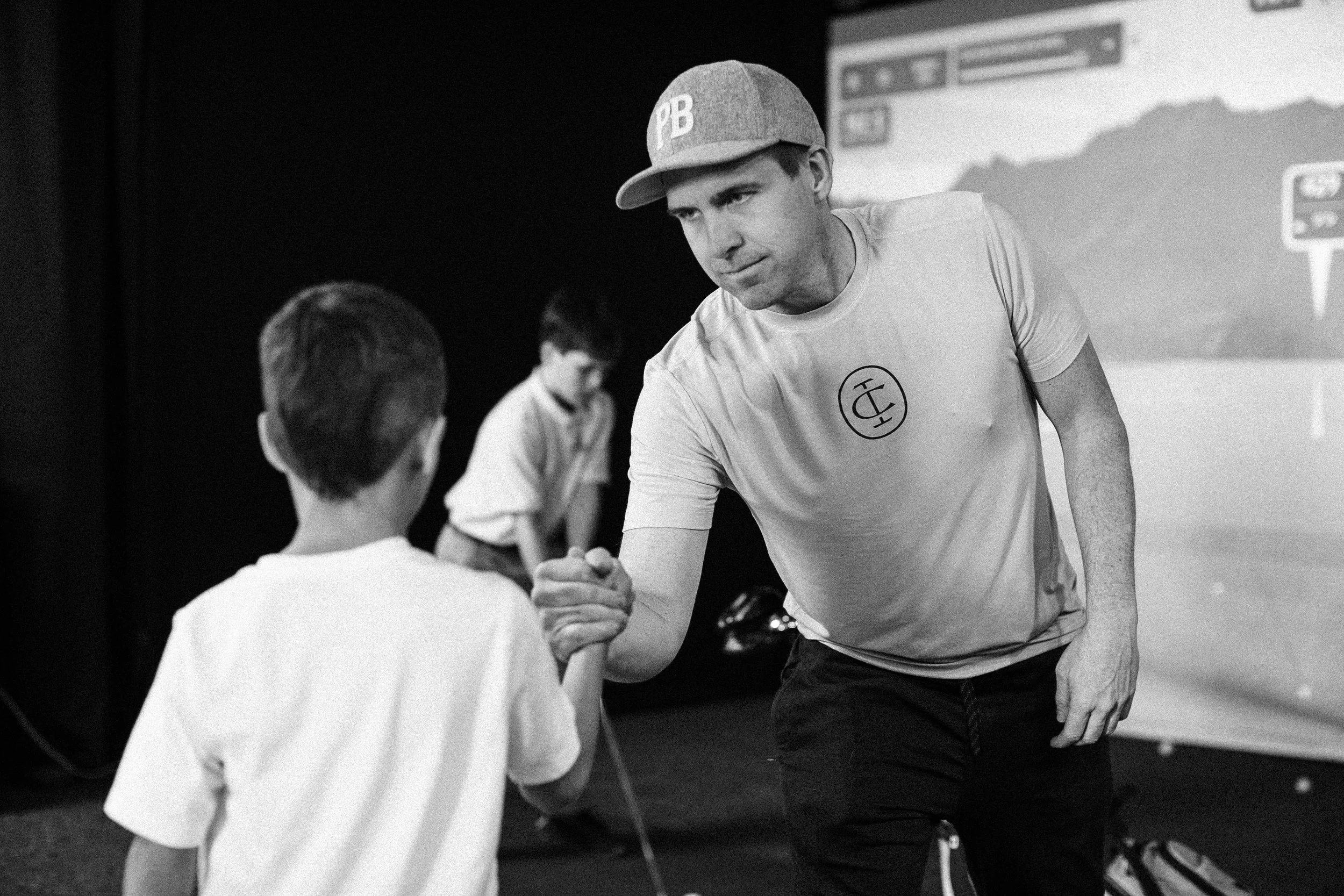 A father congratulating his son at an indoor golf simulator after taking a swing