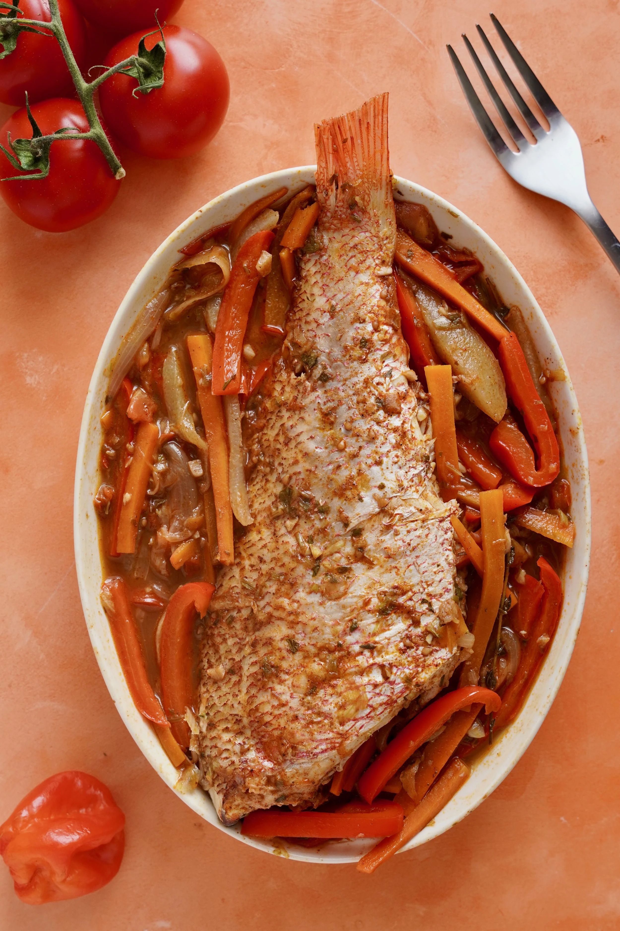 Steamed fish presented in a ceramic, oval dish on a bed of vegetables