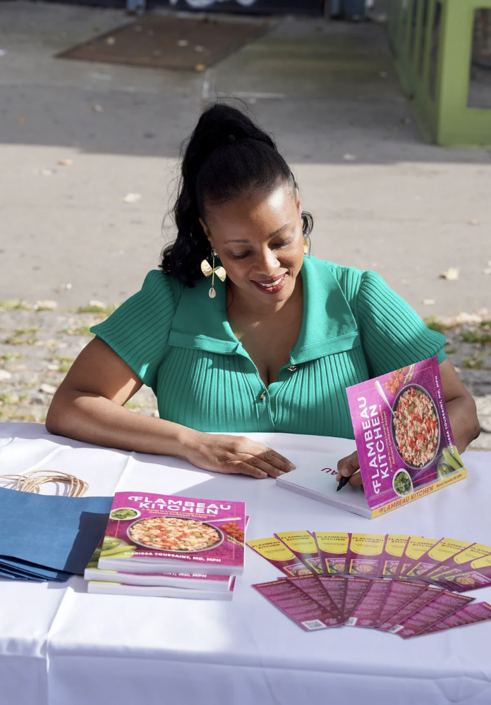 Dr. Marissa Toussaint signs copies of her cookbook Flambeau Kitchen.