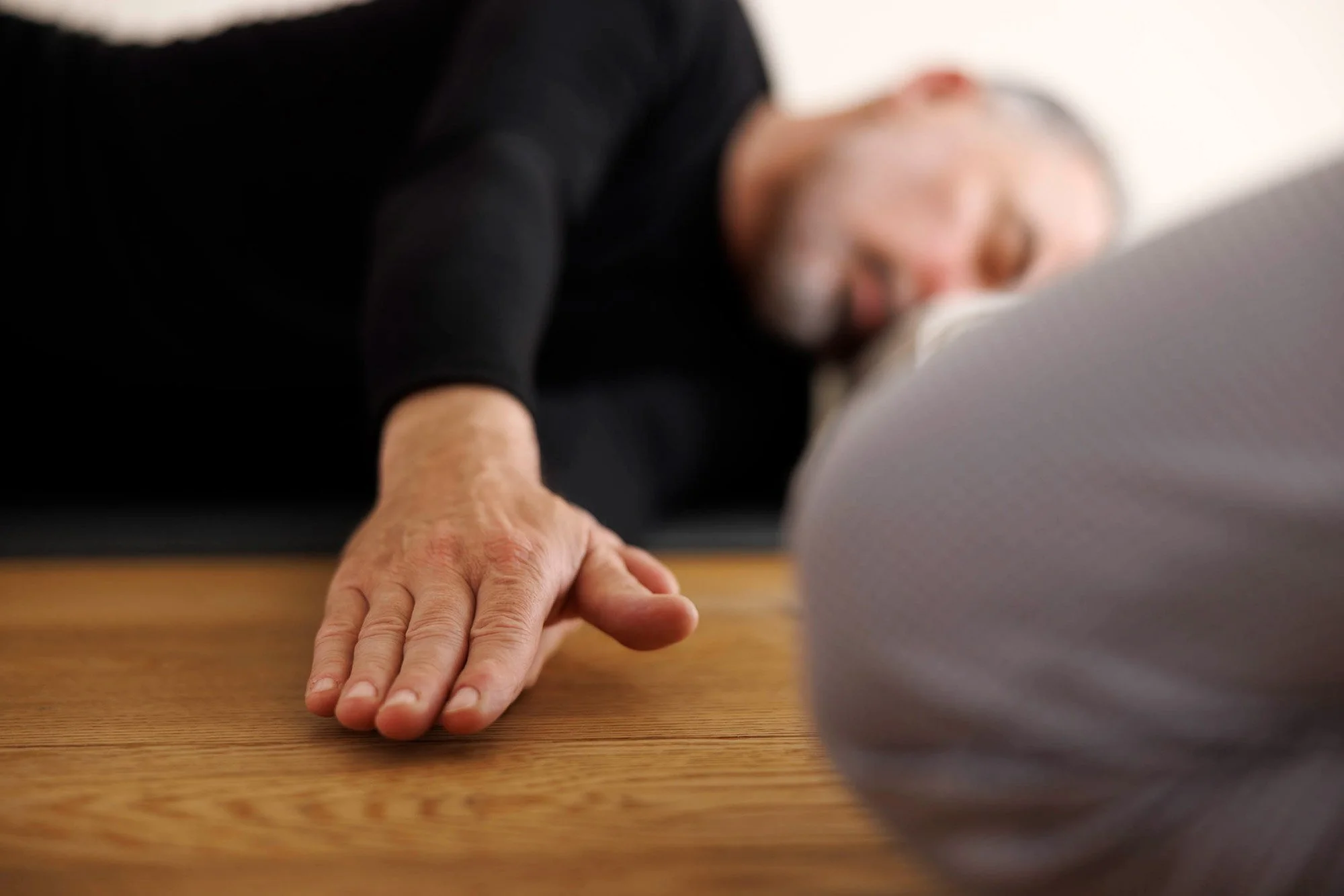 Eine Mann macht Yoga-Übungen auf einem Holzboden.