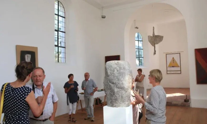 Menschen in einer Kunstgalerie, einige unterhalten sich, um eine große Skulptur in der Mitte des Raumes