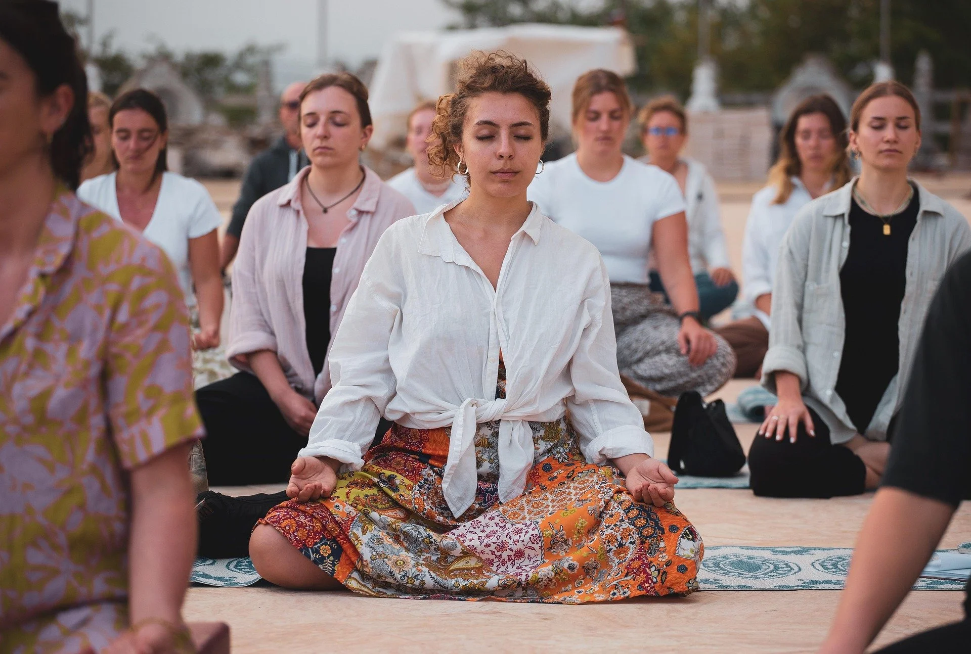 Femei în meditație la un eveniment transformațional în aer liber — workshopuri și seri tematice cu Roxana Colțea