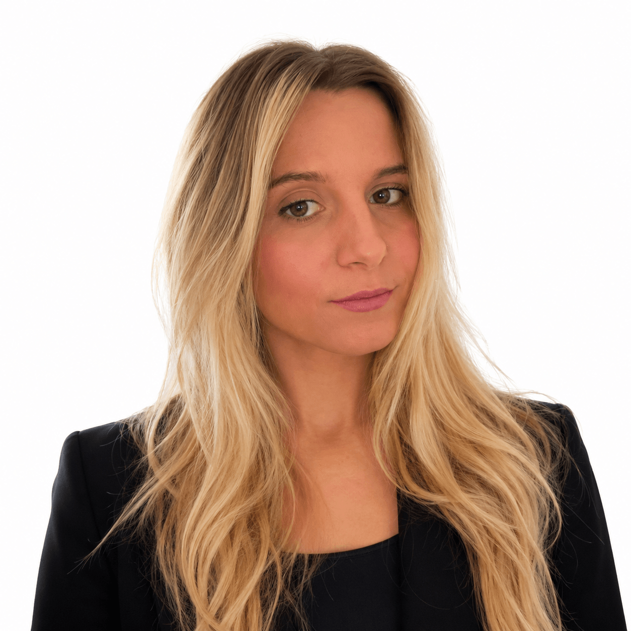 A woman with long, wavy blonde hair and light skin, wearing a black blazer, looking at the camera with a slight smile against a plain white background.