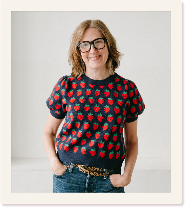 coach tammie bennett smiles at camera. she is wearing glasses and a navy sweater with strawberries on it.