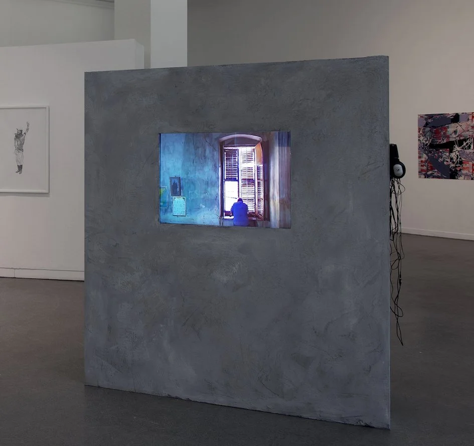 Sylvia Henze, Aussicht, Videoinstallation: Ein in eine grob verputzte Wand eingelassener Bildschirm zeigt die Innenansicht eines Fensters mit geschlossenen Läden, durch die die Sonne fällt. Das Wandelement steht frei in einem Ausstellungsraum