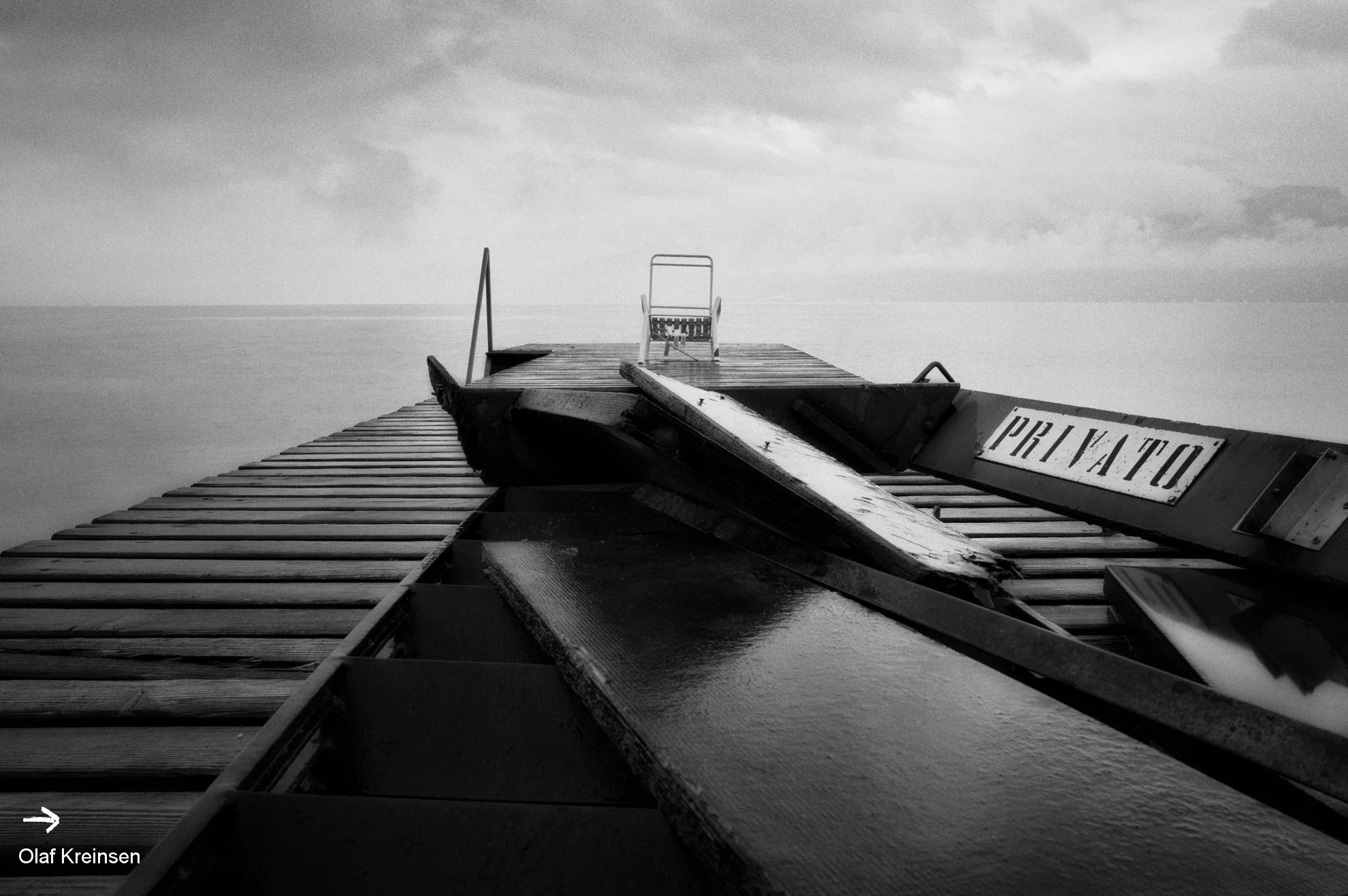 Olaf Kreinsen, Lago Silenzioso 116, 2012 - Foto Diasec oder Hanemühle Fine Art, s/w: Steg mit dem Schild "Privato" und Sonnenstuhlskelett am Gardasee