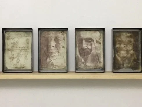 Sylvia Henze, ZEIT|EN, 2001 Videostill - eine sich in Wasser auflösende Porzellankugel vor dunkle. Hintergrund. Weiße Schlieren und Porzellanstaub, der sich am Boden um die Kugel ablagert. 