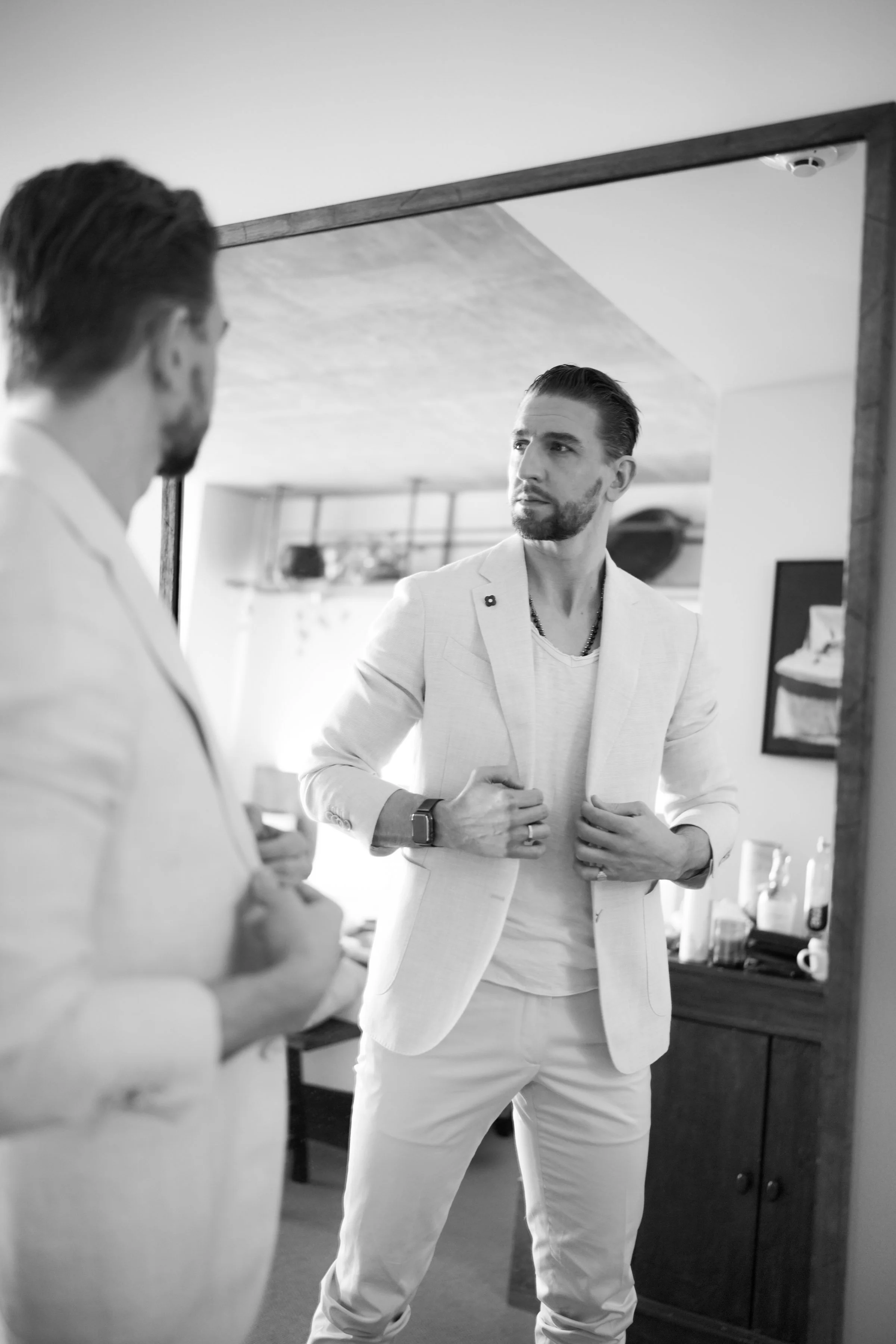 modern groom portrait adjusting suit in mirror