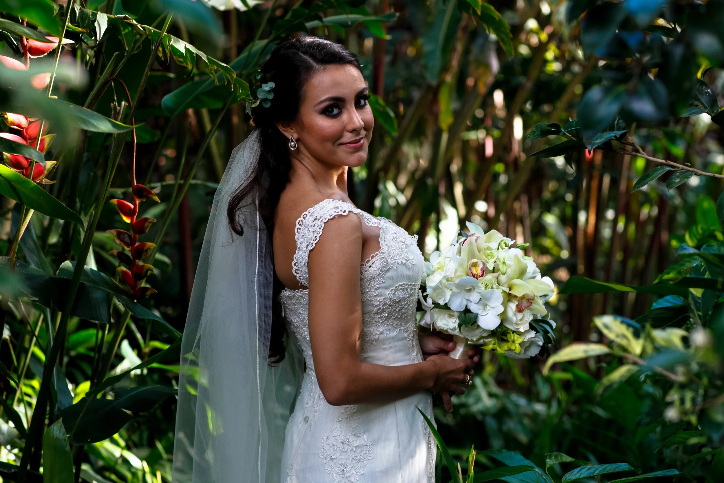 A soft over-the-shoulder portrait reveals intricate lace detailing and a luminous bouquet, blending elegance with a candid feel.