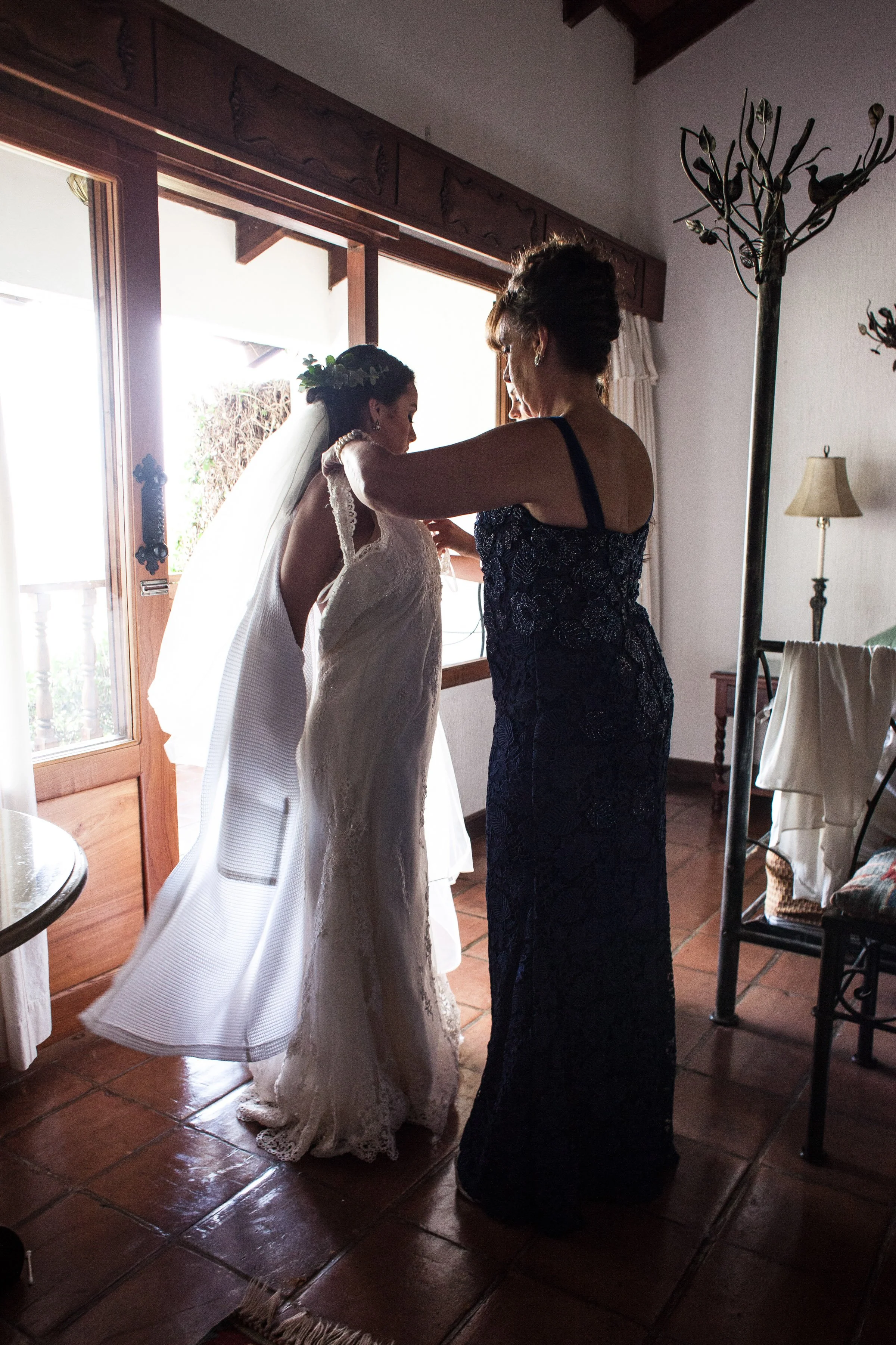 A quiet, intimate moment as the bride is helped into her gown, capturing the emotion and anticipation of the day.