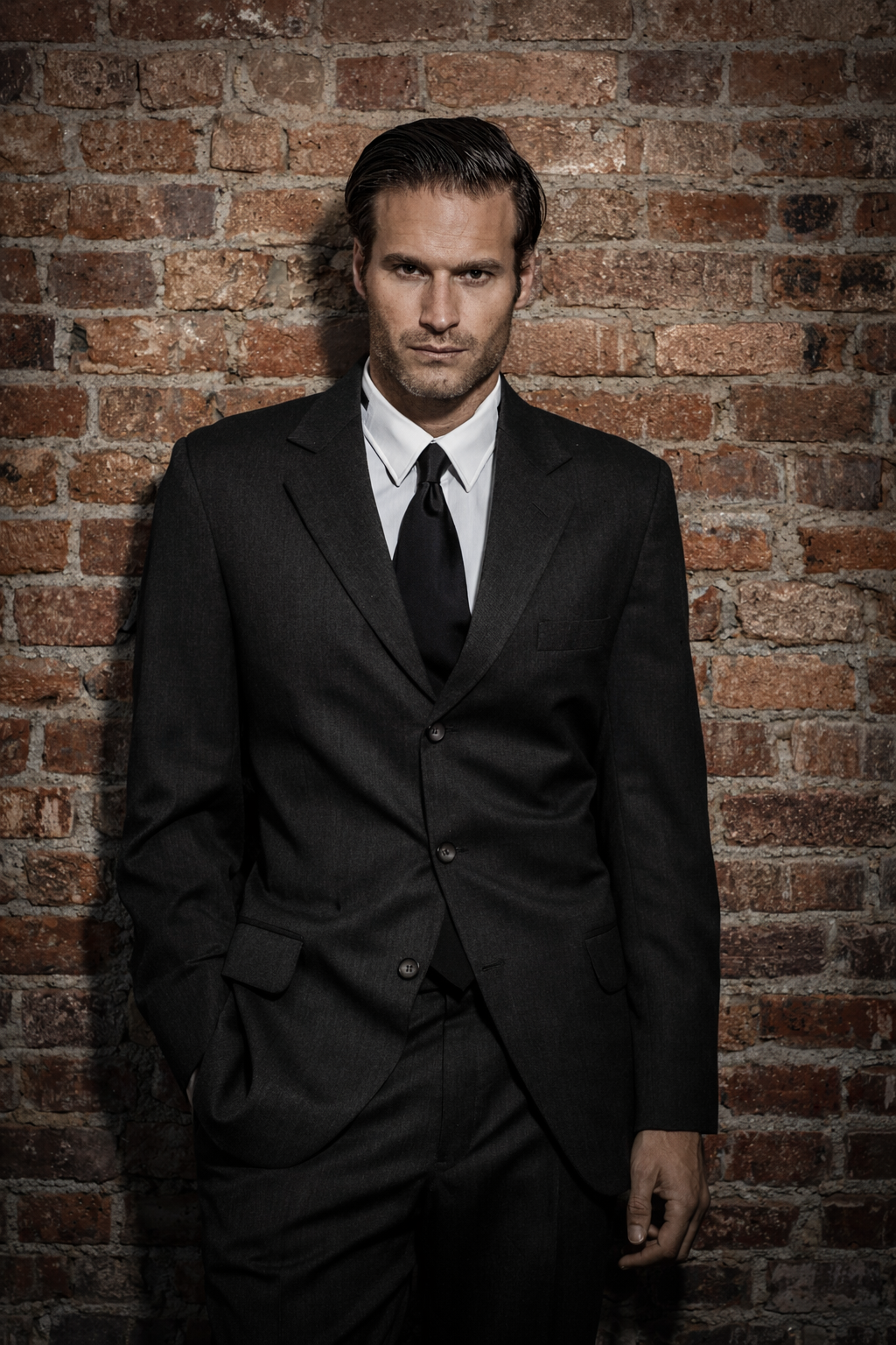 modern groom portrait in suit with brick wall background