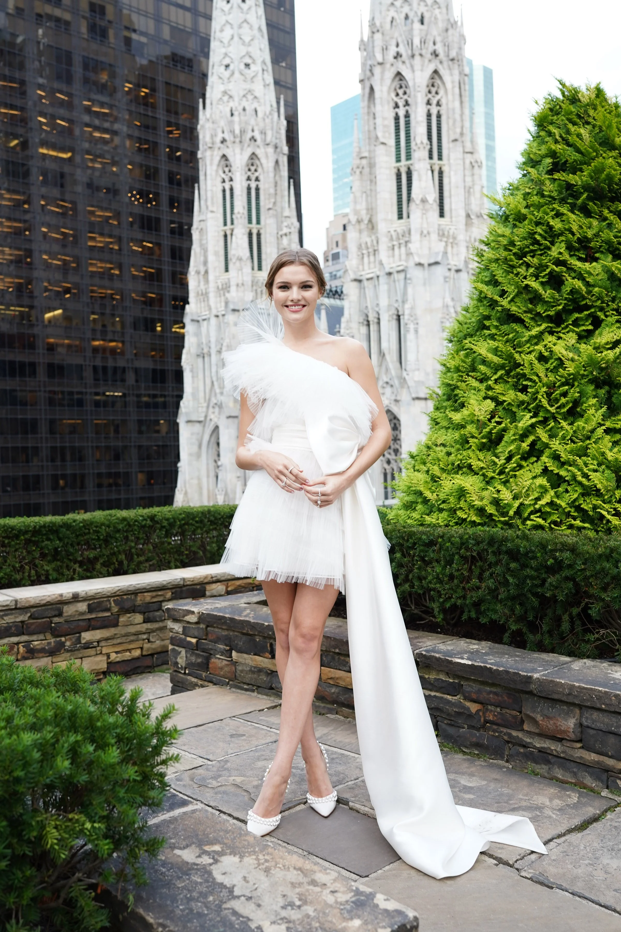 A playful, fashion-forward bridal portrait featuring a short silhouette and soft textures, set against the city skyline.
