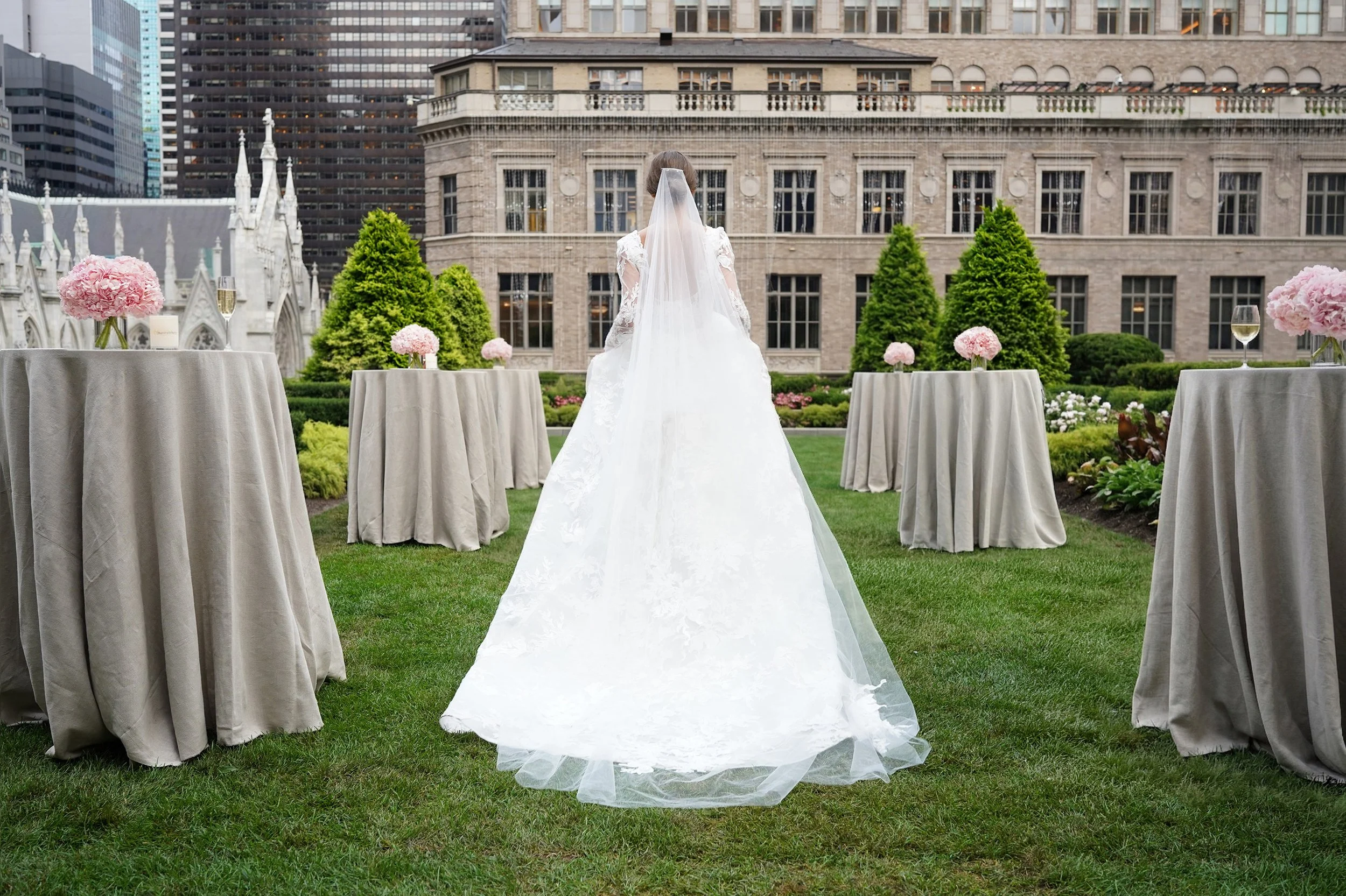 back view of the full gown and veil on the lawn between cocktail tables