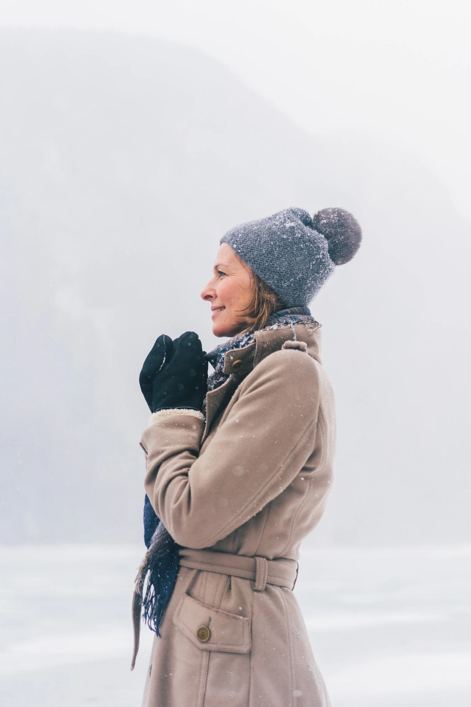 Frau in Winterkleidung, Mütze und Schal in einer verschneiten Landschaft, Winter, kalt, friert