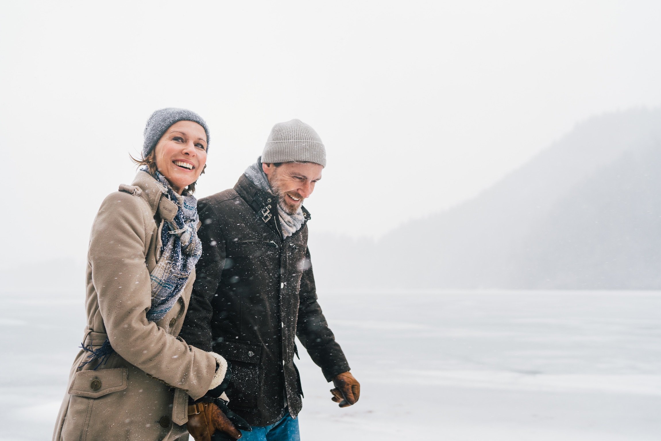 Zwei lachende Menschen im Winterkleidung im Schneewald.