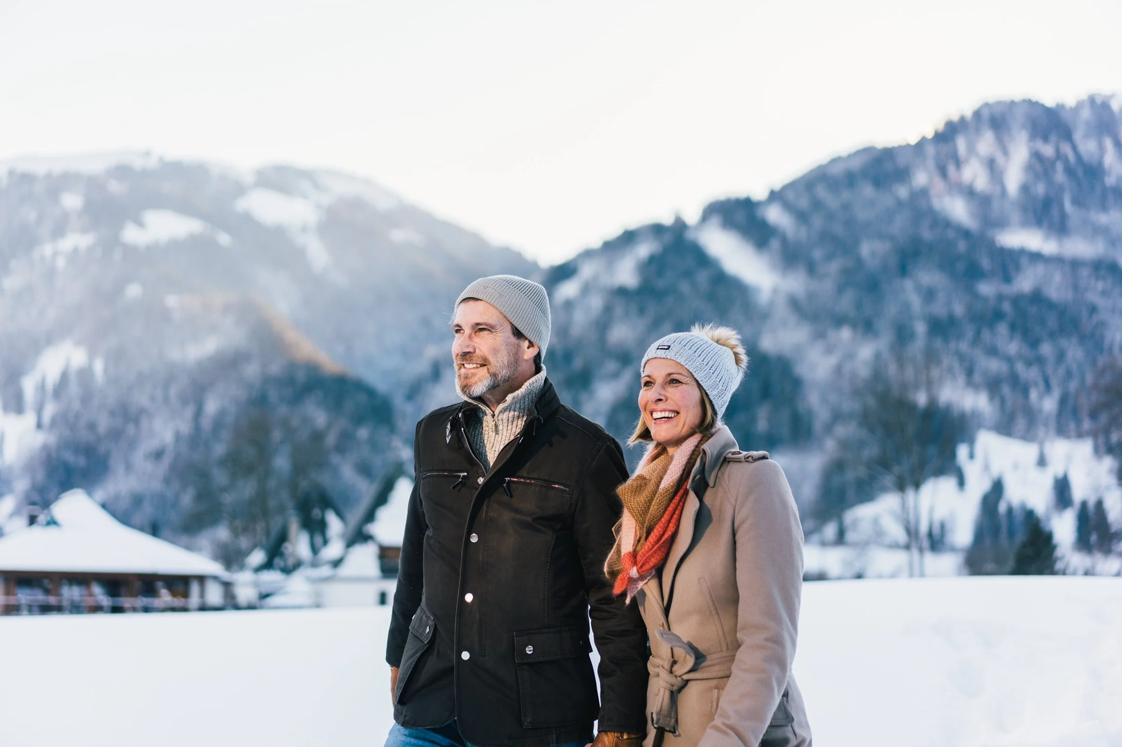 Ein lachendes Paar in Winterkleidung in einer verschneiten Berglandschaft