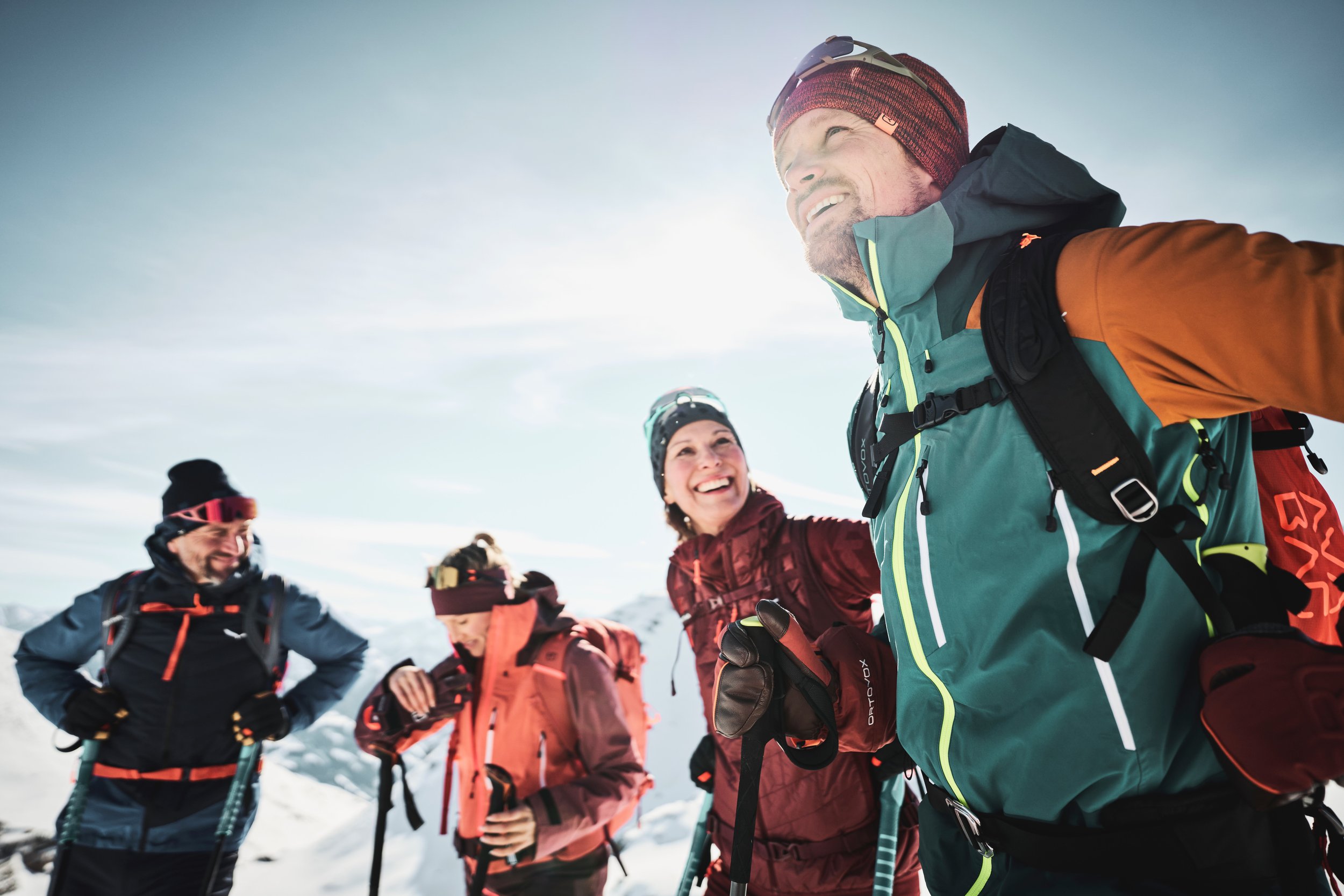 Gruppe von Menschen beim Bergsteigen in Schutzausrüstung in einer Schneelandschaft bei sonnigem Himmel.