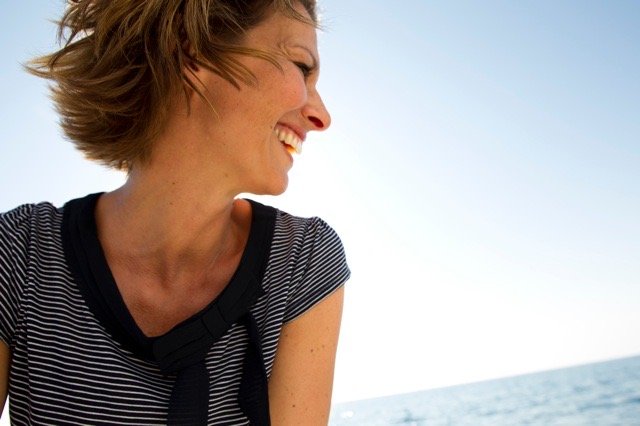 Lächelnde Frau mit kurzen Haaren, im Meeresblick, bei sonnigem Wetter