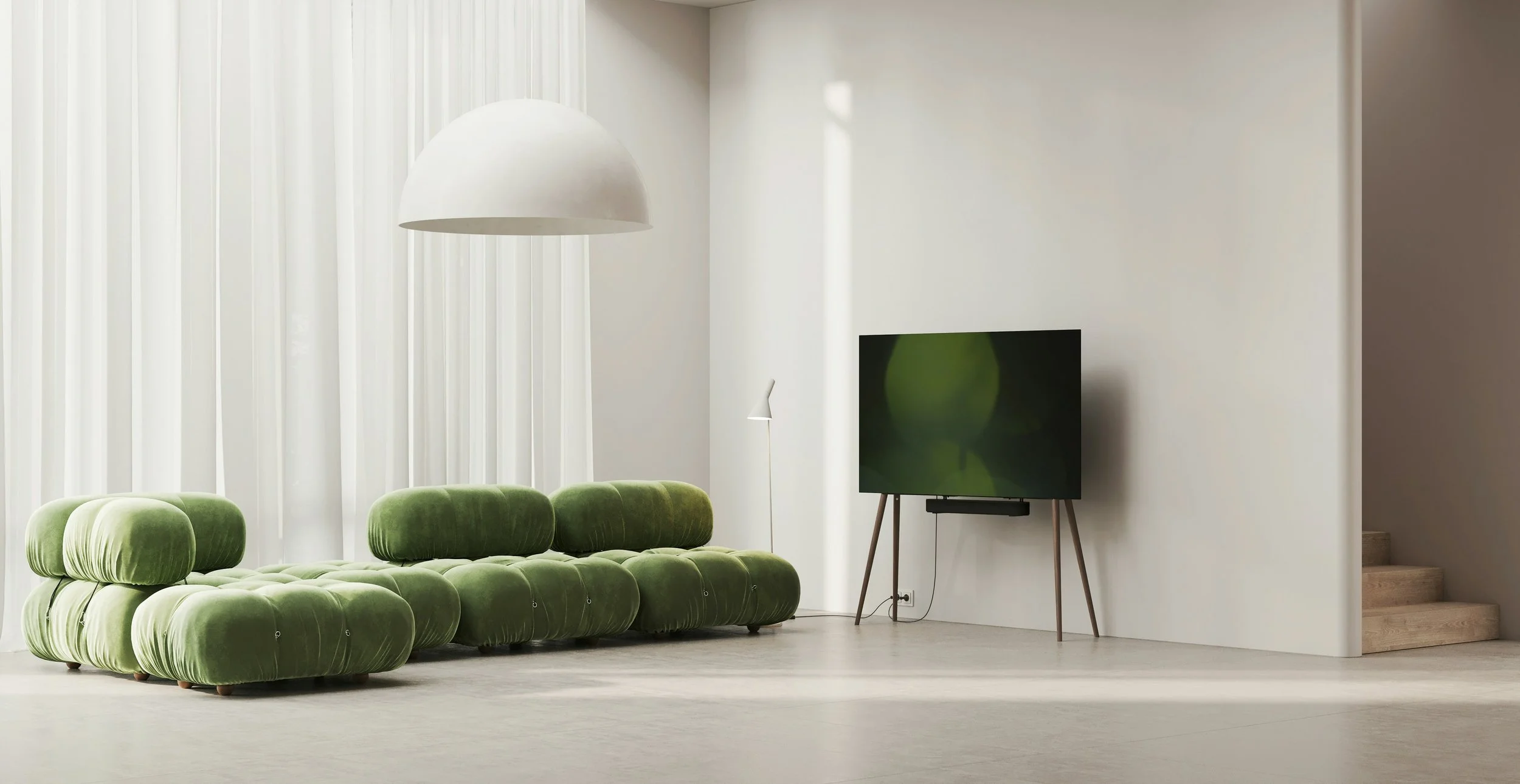 Modern living room with a green velvet sofa, large white pendant light, flat-screen TV on wooden stand, white walls, window with white curtains, and a staircase in the background.