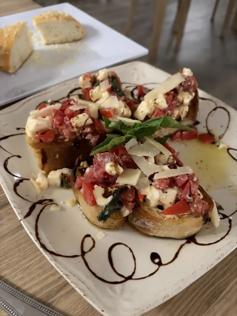 Plate with bruschetta topped with tomatoes, cheese, basil, and balsamic drizzle,