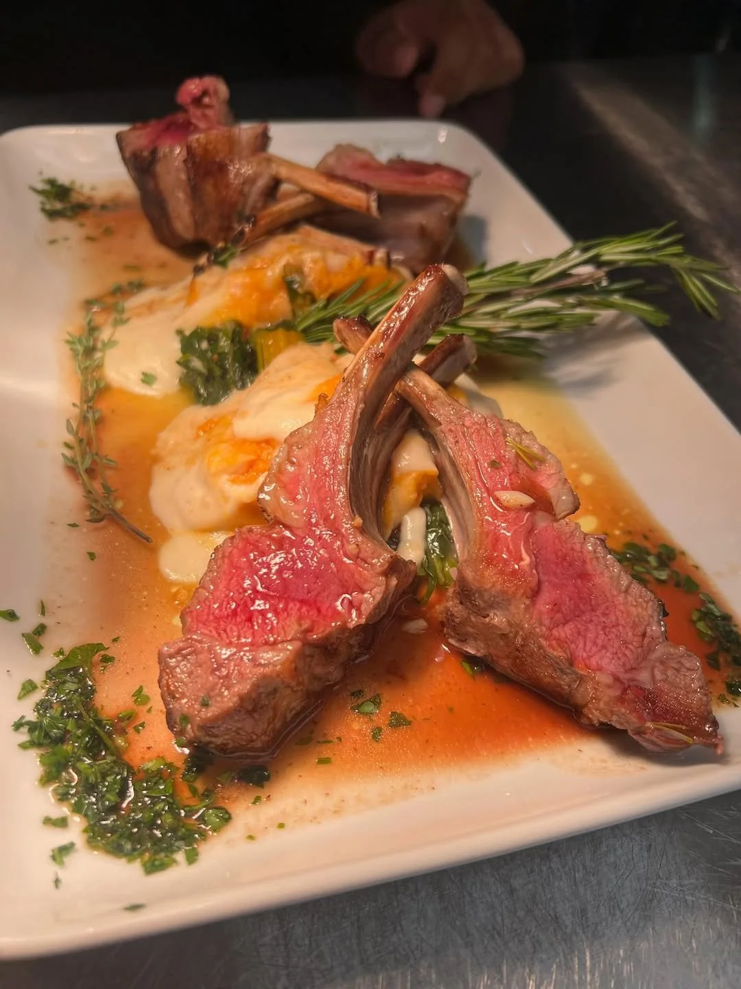 Plate of cooked lamb chops with herbs, served with egg, greens, and sauce.