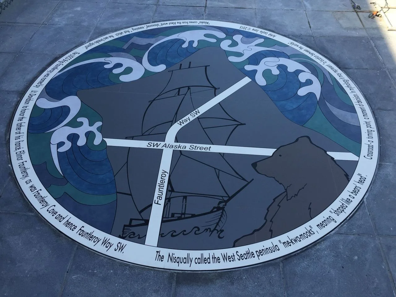 A circular historical marker on the ground depicting a pirate ship and stylized waves with labeled streets and a bear silhouette, detail about the West Seattle peninsula and Fountleroy Way SW.
