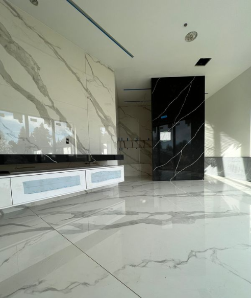 Modern interior space with marble floors and walls, including a black marble column, and a white marble wall with black veining.