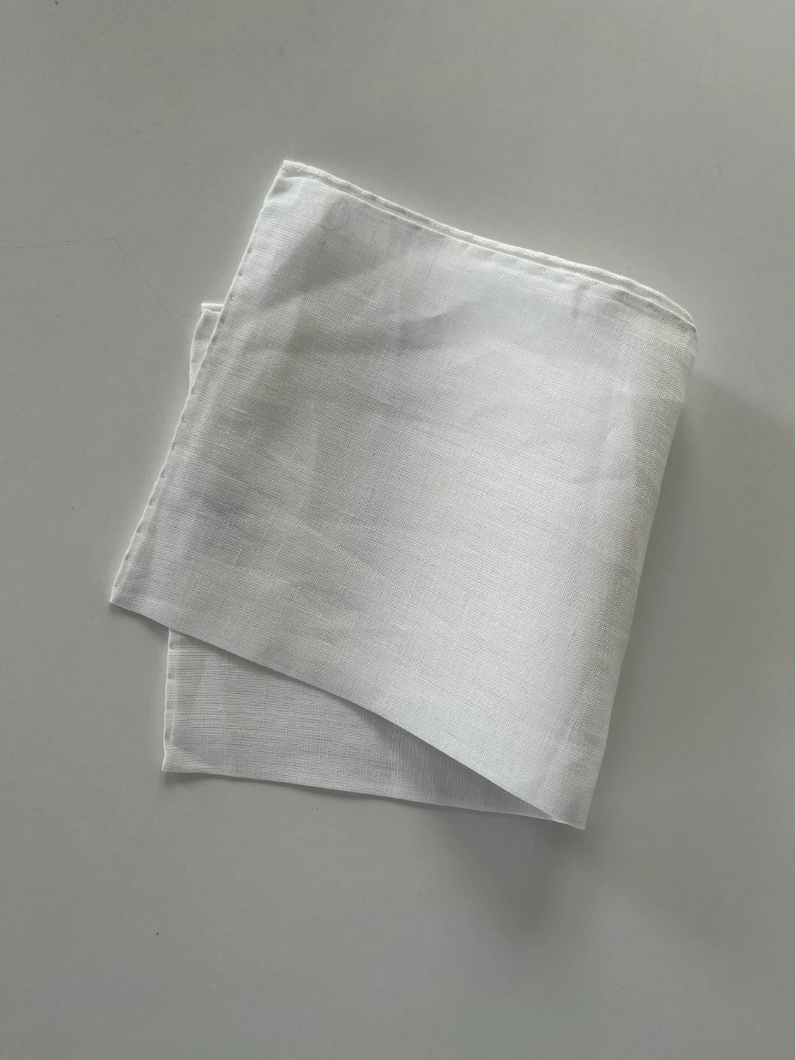 White linen pocket square with hand-rolled hems