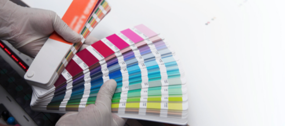 Mano sosteniendo una tarjeta de muestra de colores, como en una carta de colores de pintura o diseño.