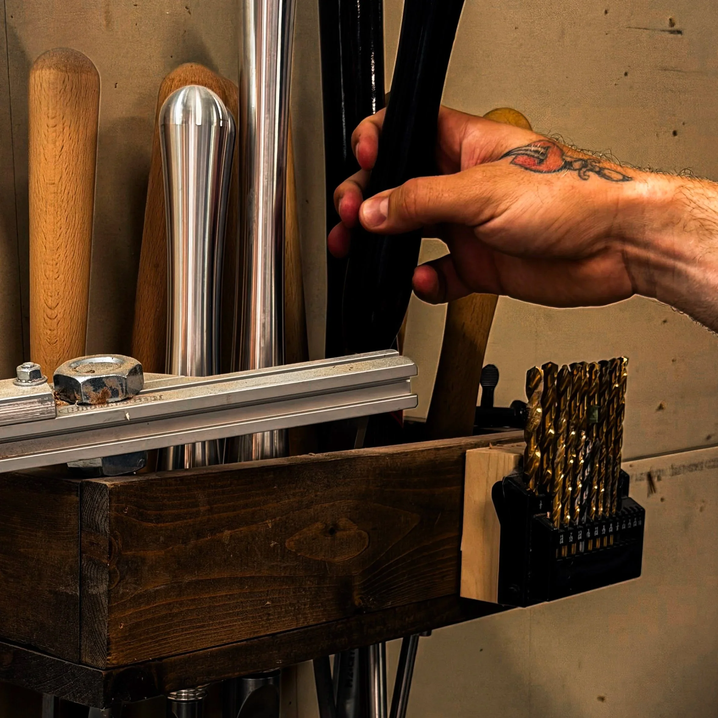 Handcrafted hardwood tool rack holding woodturning tools and drill bits in a woodworking shop by Blackburl Works.