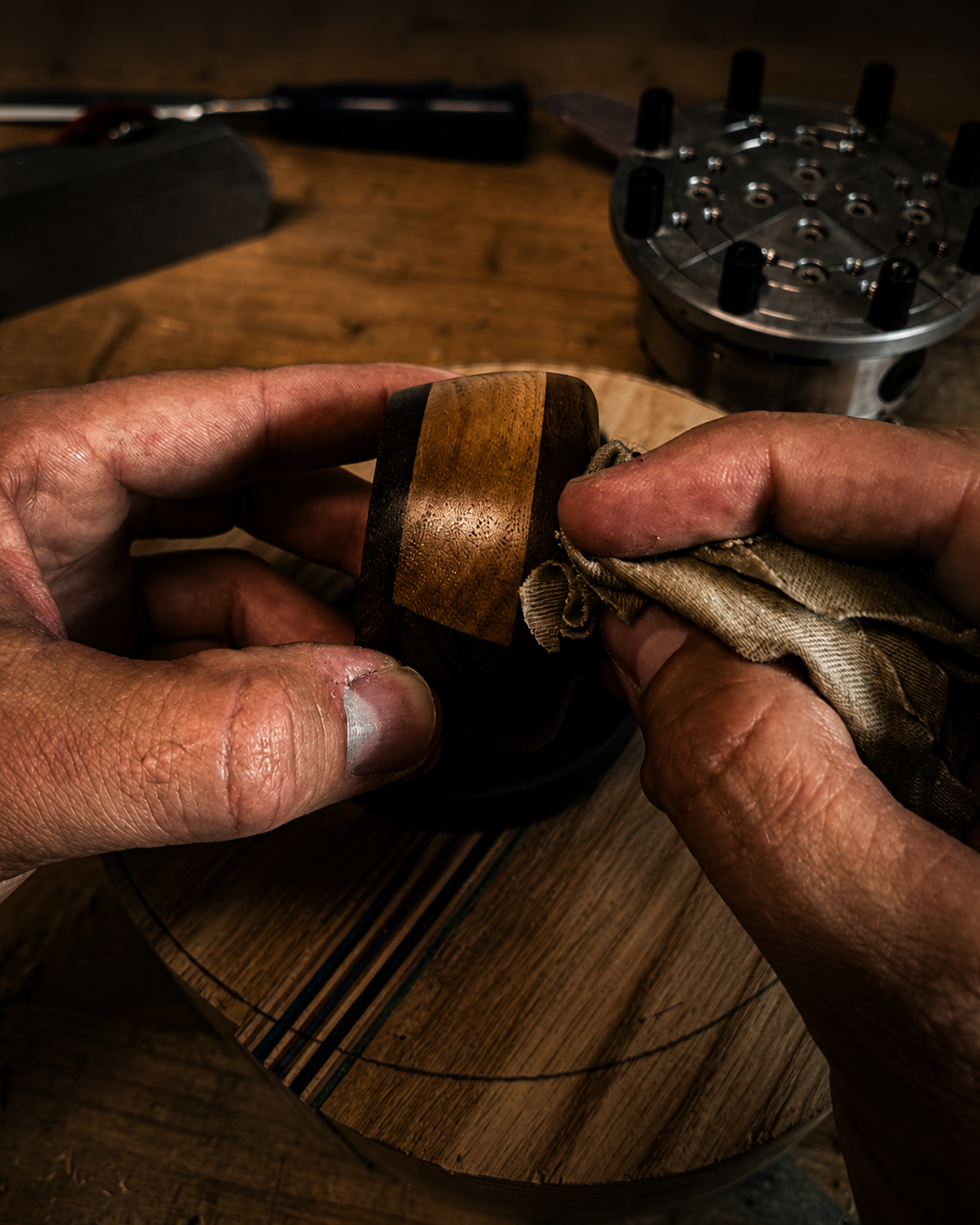 Hands applying finish to a handcrafted hardwood bowl with recycled skateboard accent.