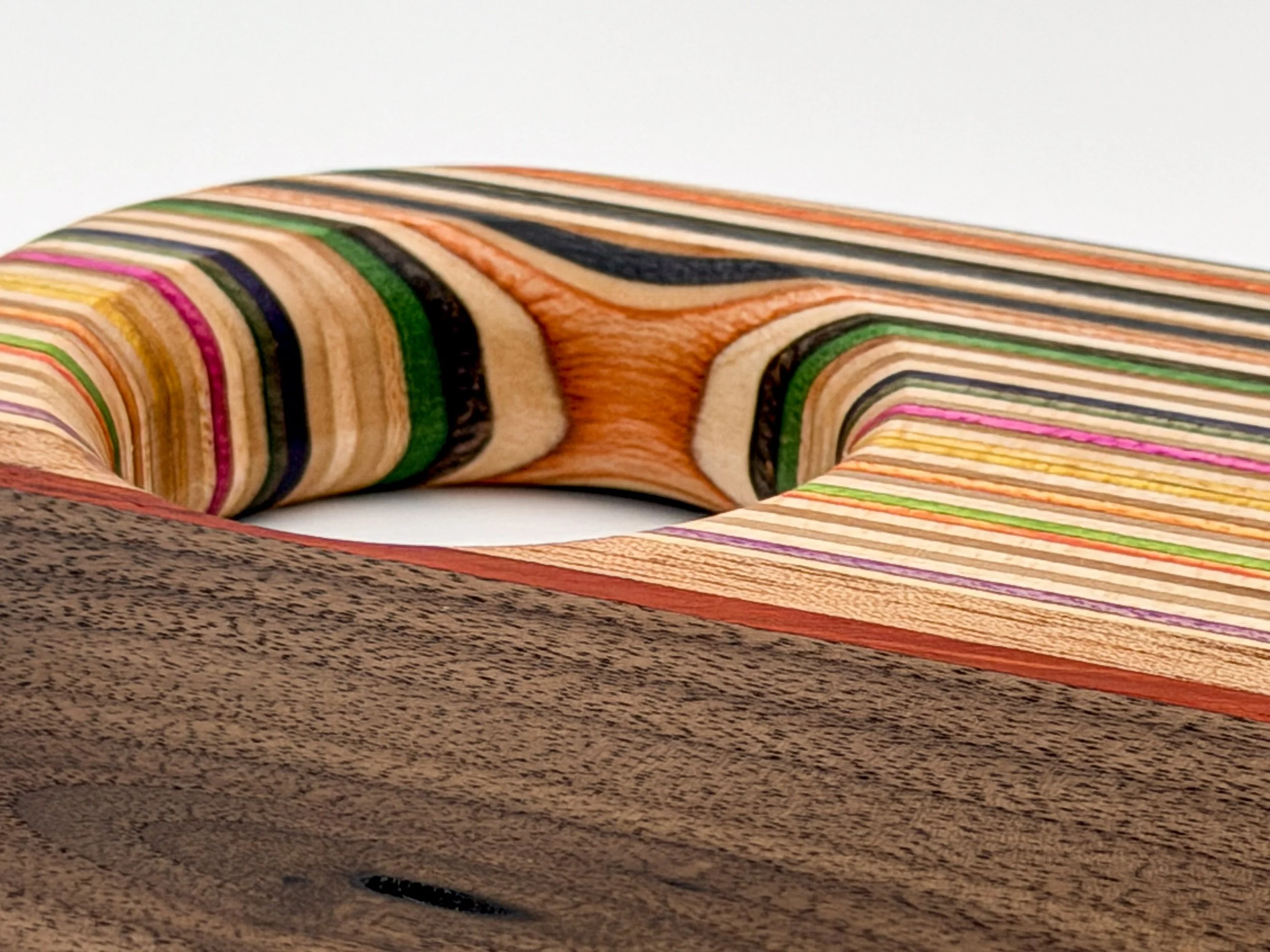 Close-up of a handcrafted serving board made from layered recycled skateboard wood and walnut. blackburl works  one of one