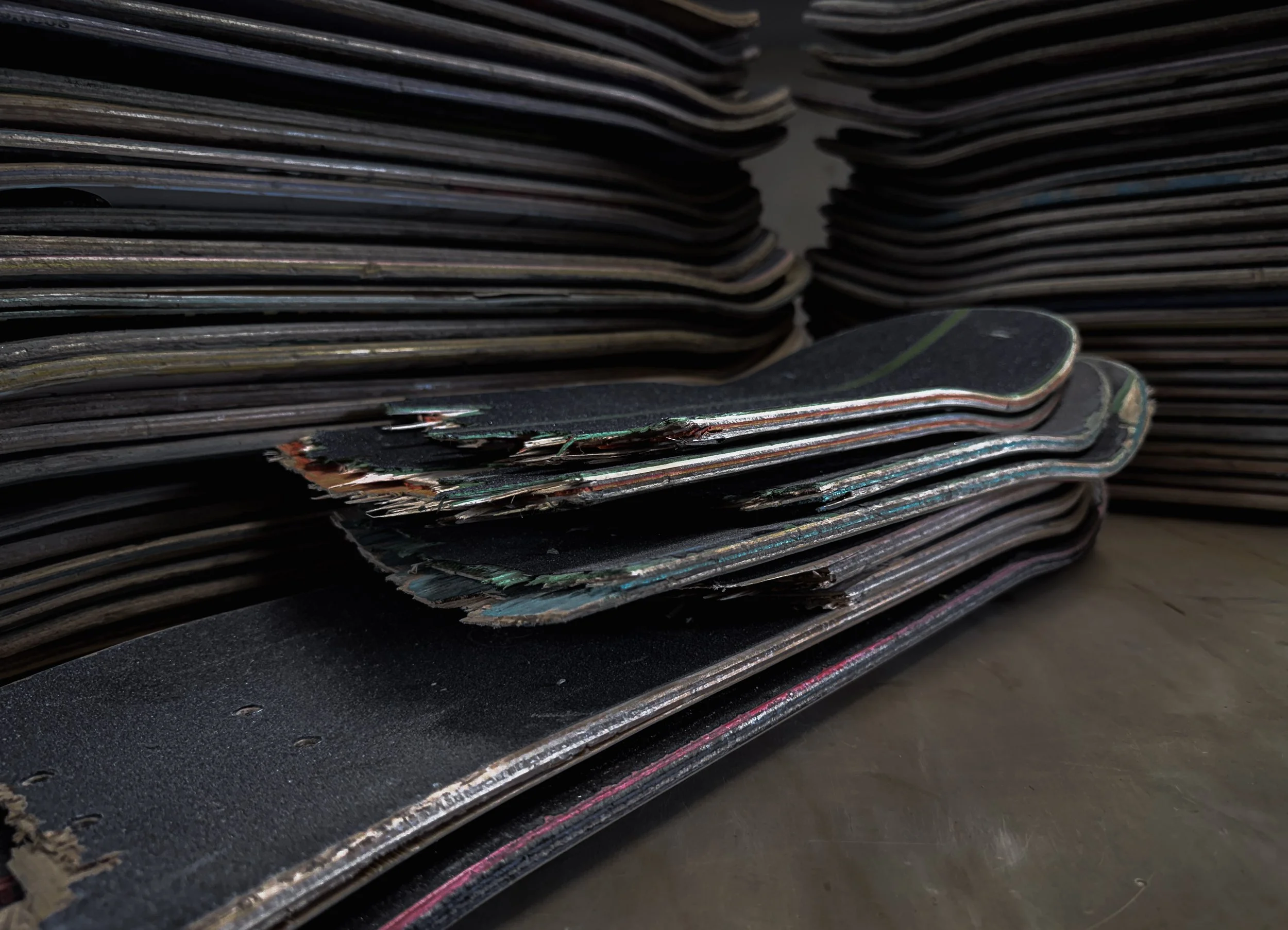 Close-up view of stacked skateboards with worn-out decks and grip tape.