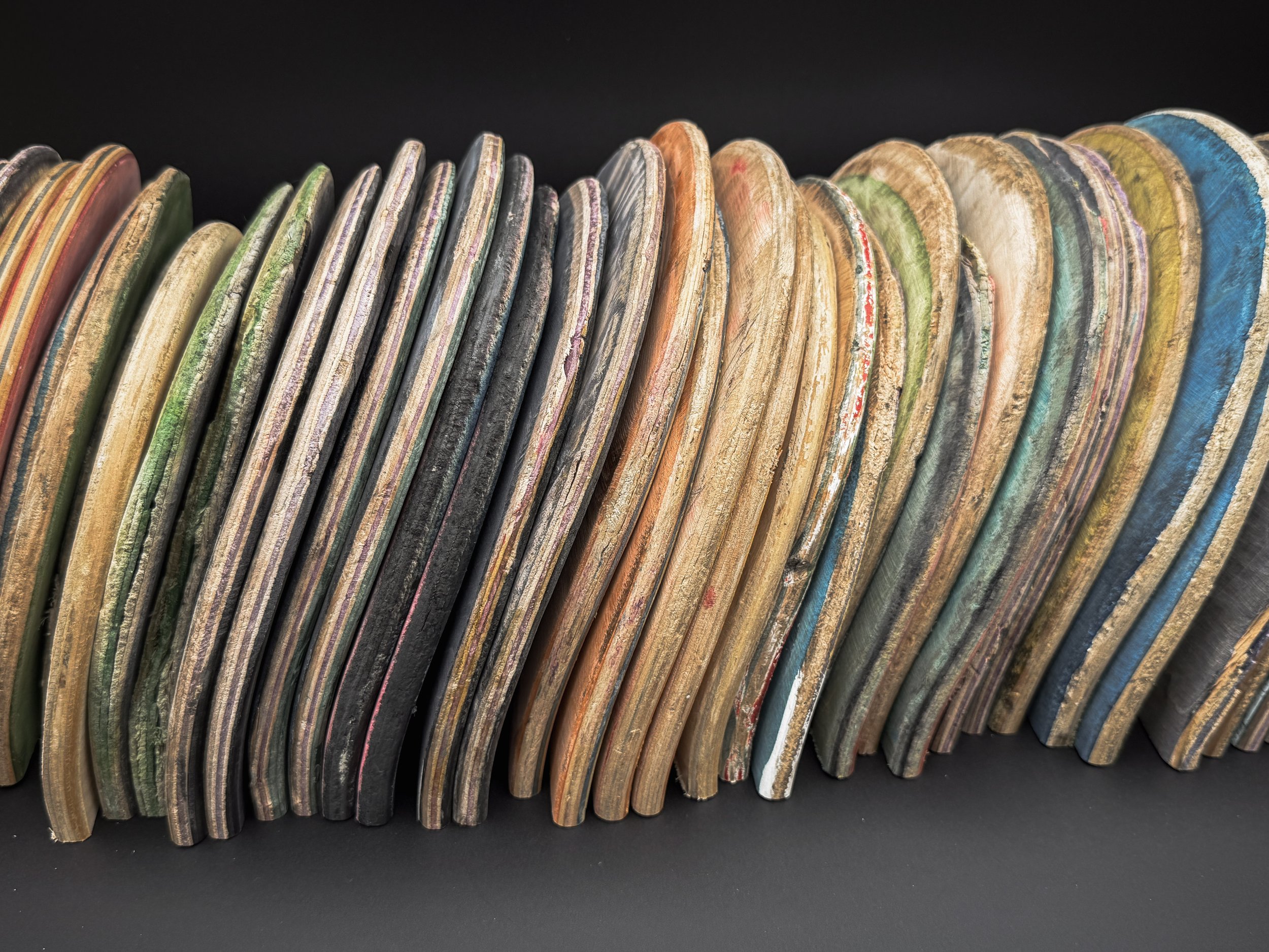A collection of colorful skateboard decks leaning against a black background.