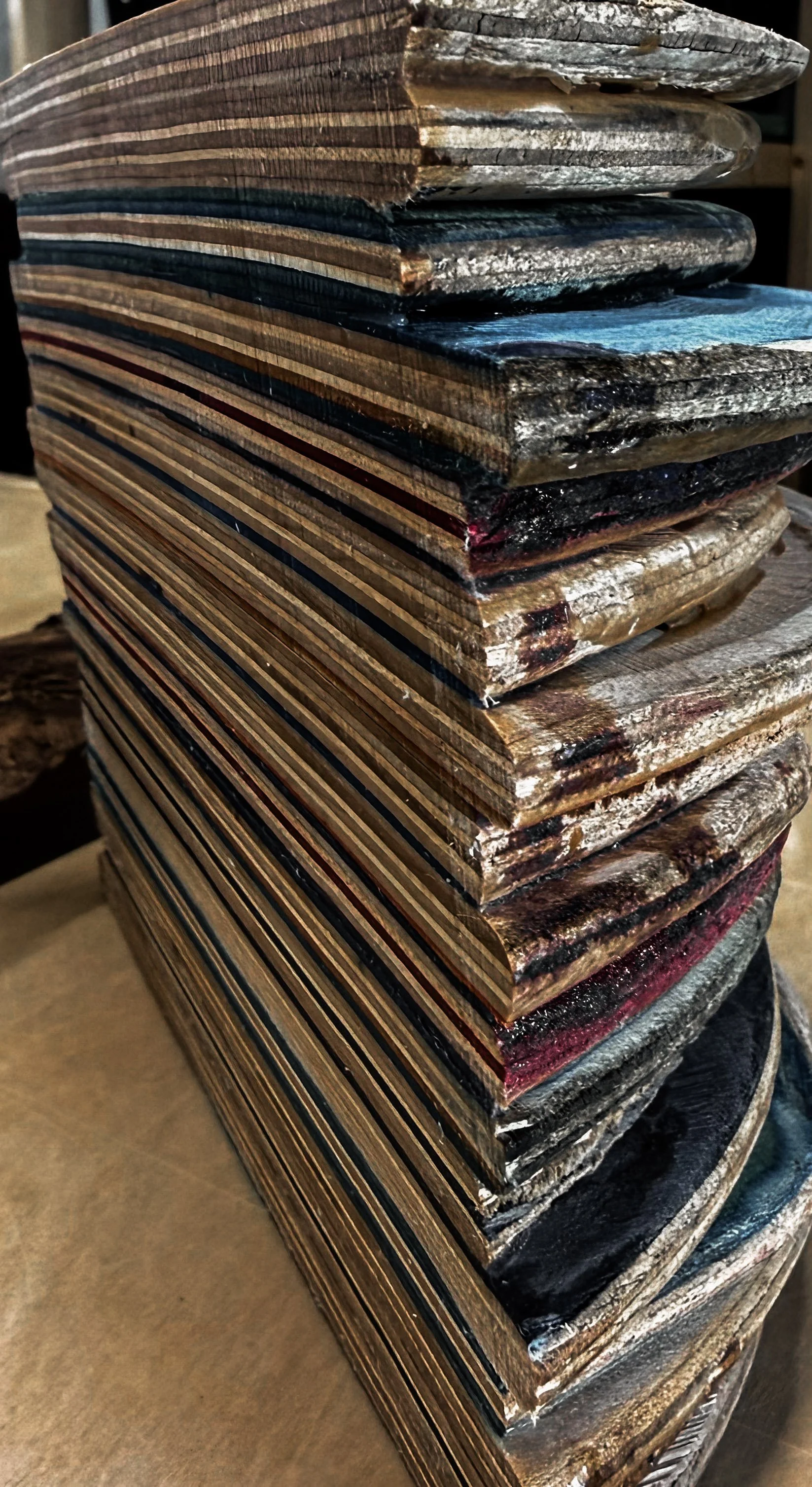 Stack of wooden planks with varying colors and textures, some with painted or stained surfaces.