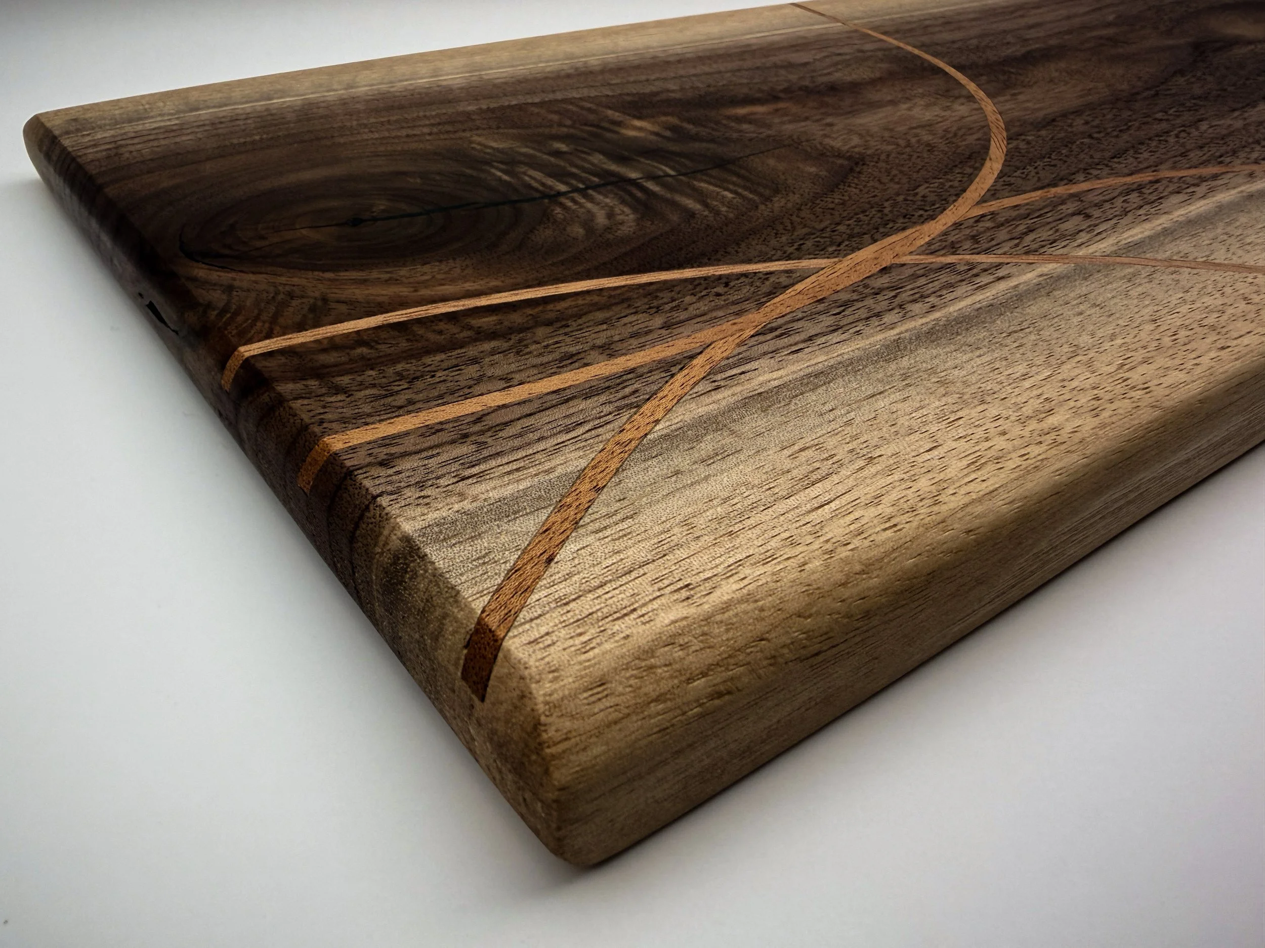 Close-up of a wooden cutting board with decorative inlay patterns. made by blackburl works. mosiac recycled skateboard inlay.