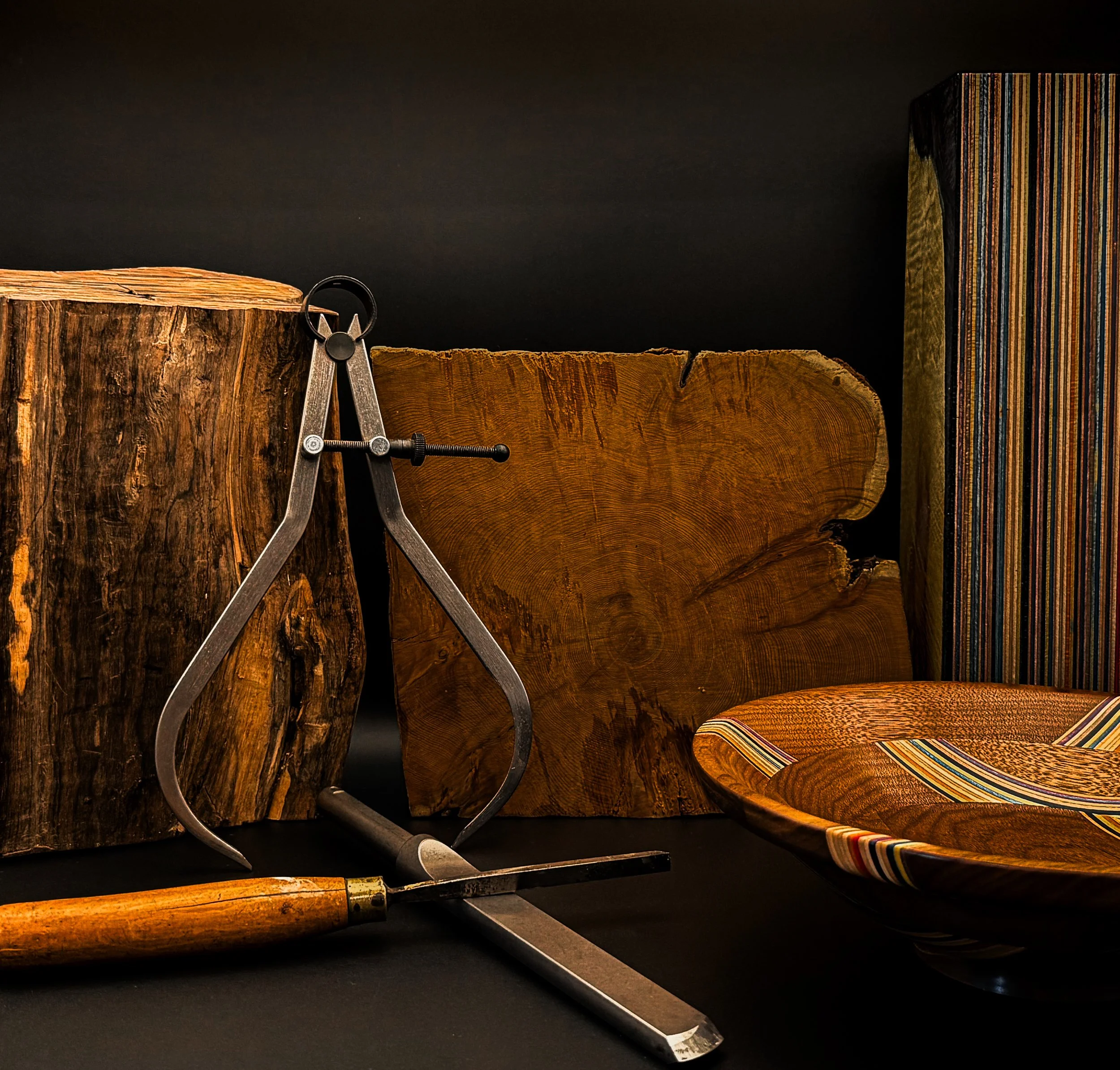 Traditional woodturning tools displayed with premium hardwoods, recycled skateboard material, and a handcrafted wooden bowl in the Blackburl Works workshop.