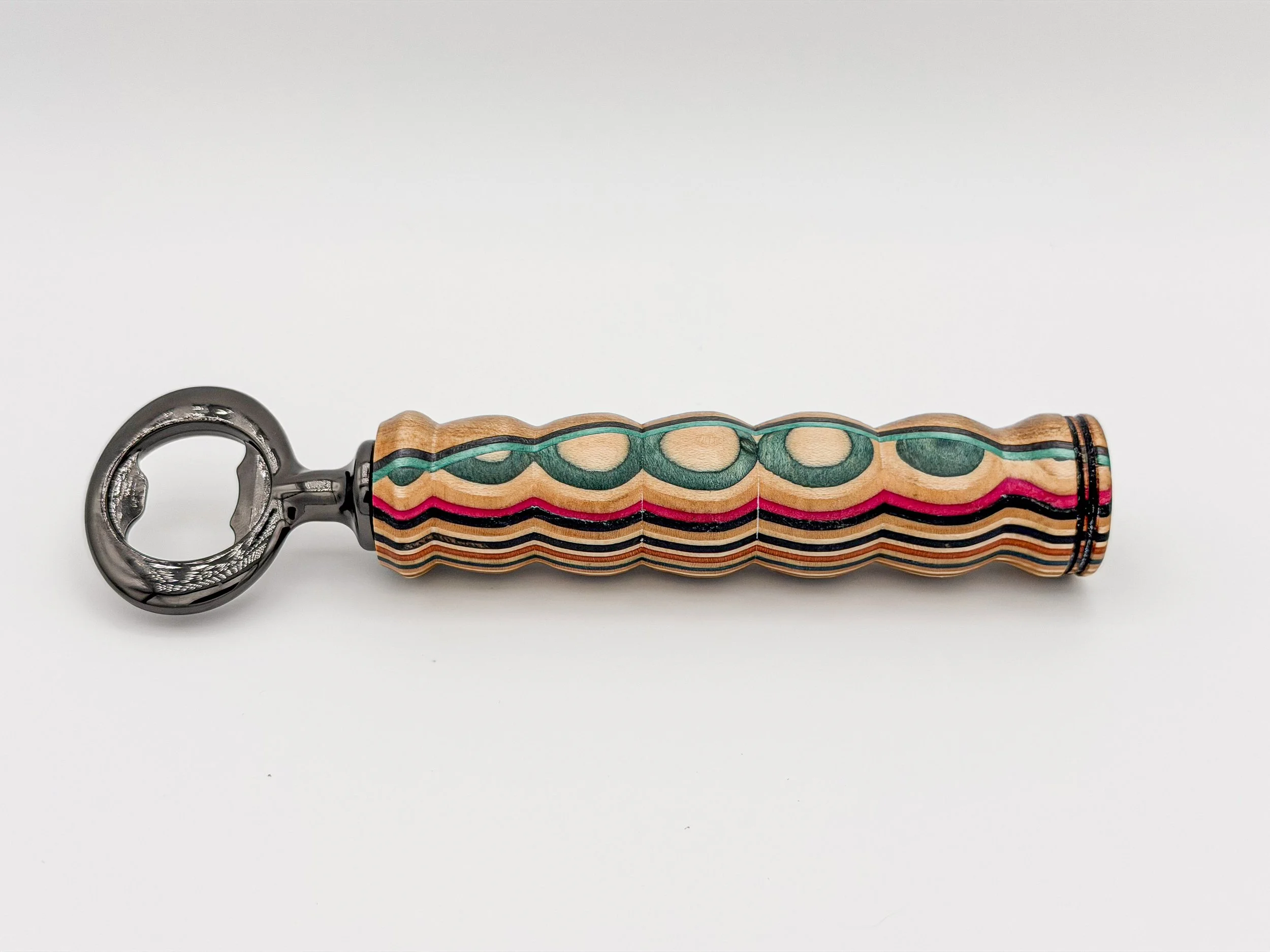 A colorful set of keys with a multicolored, striped, and patterned handle, lying flat on a plain white surface.