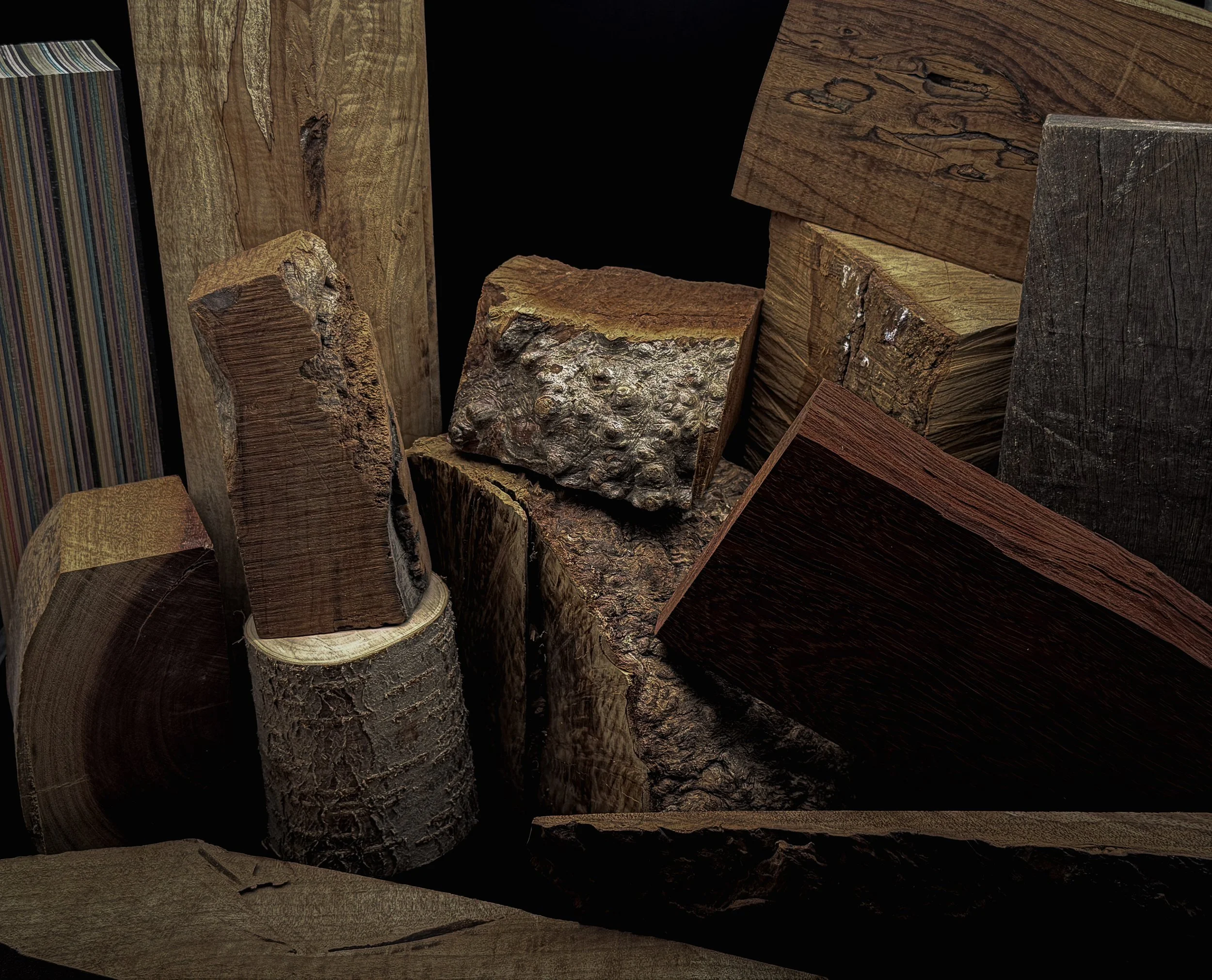 Close-up of various wooden logs and planks of different sizes and textures stacked together.