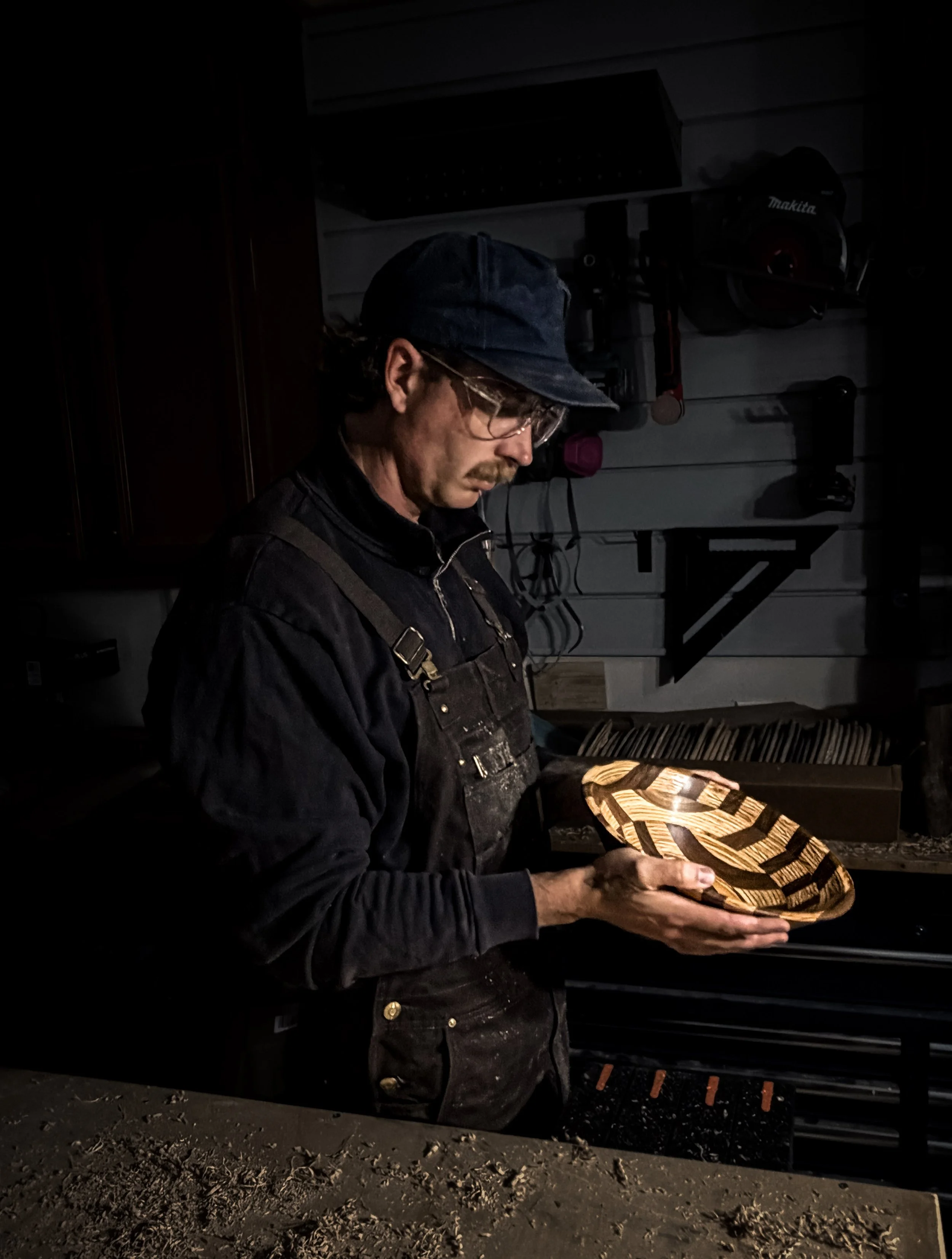 Woodworker inspecting a handcrafted segmented hardwood bowl in the Blackburl Works workshop.